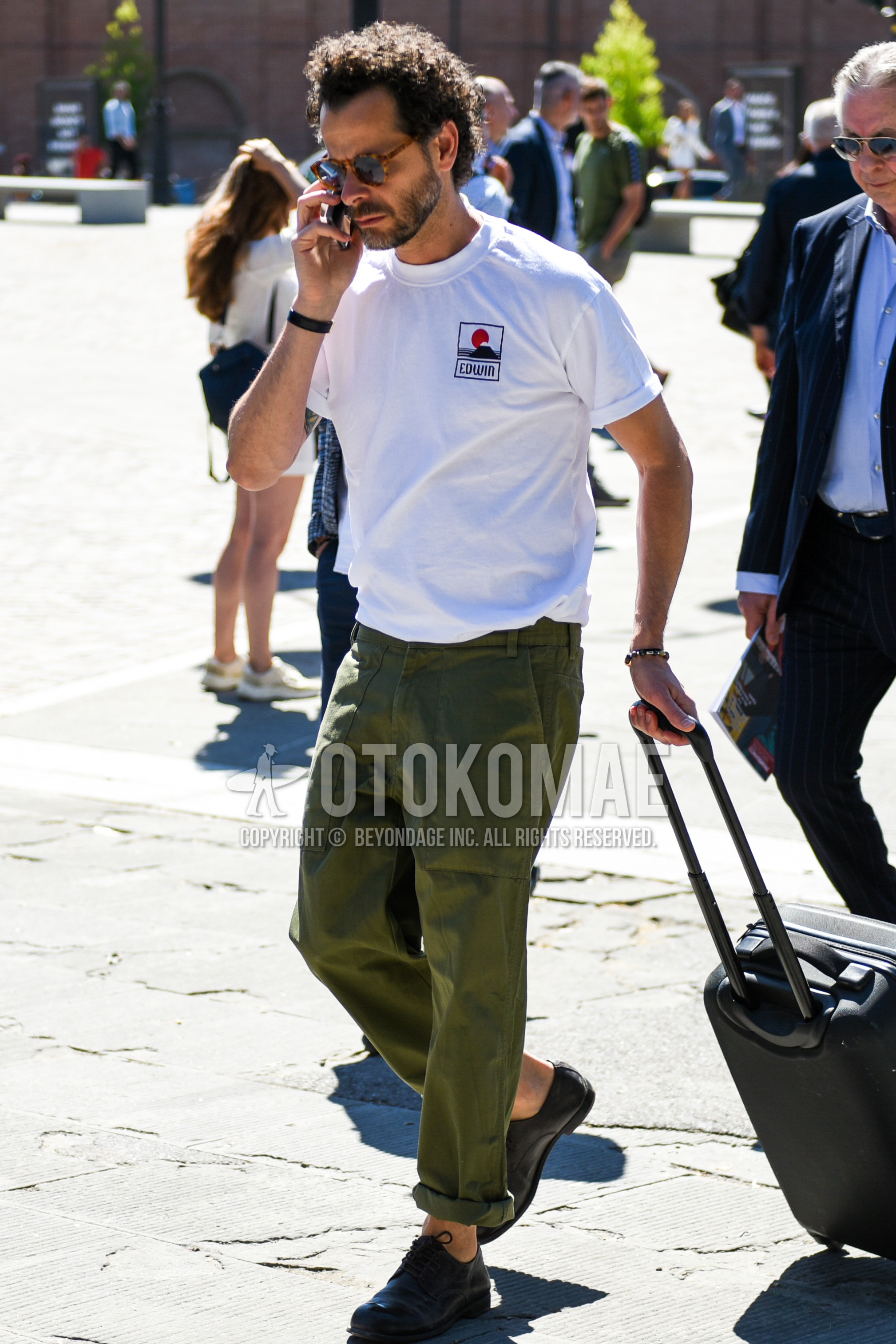 Men's summer outfit with brown tortoiseshell sunglasses, white one point t-shirt, olive green plain chinos, black straight-tip shoes leather shoes.