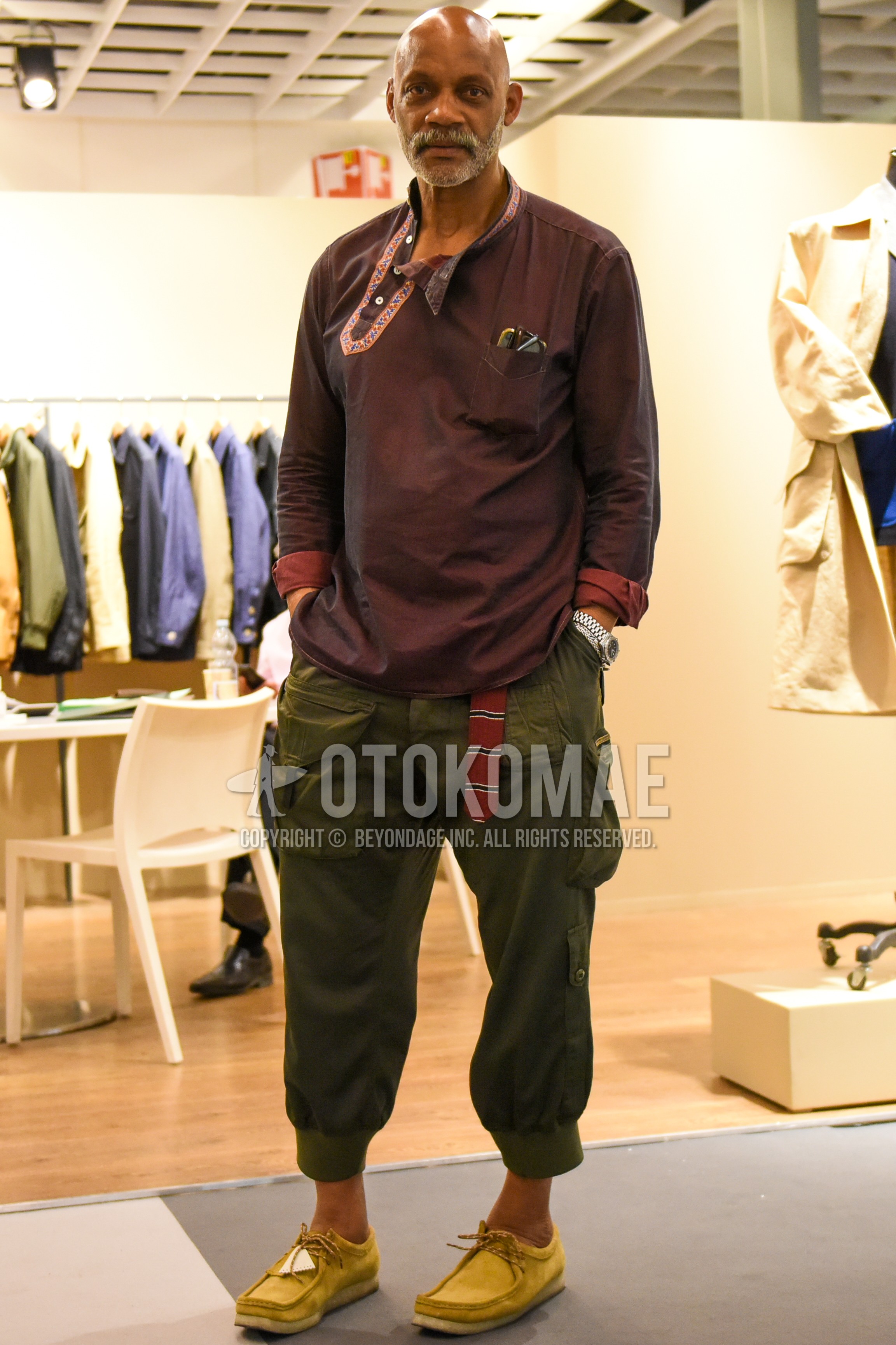 Men's spring summer autumn outfit with brown plain shirt, red horizontal stripes tape belt, olive green plain cargo pants, yellow moccasins/deck shoes leather shoes.