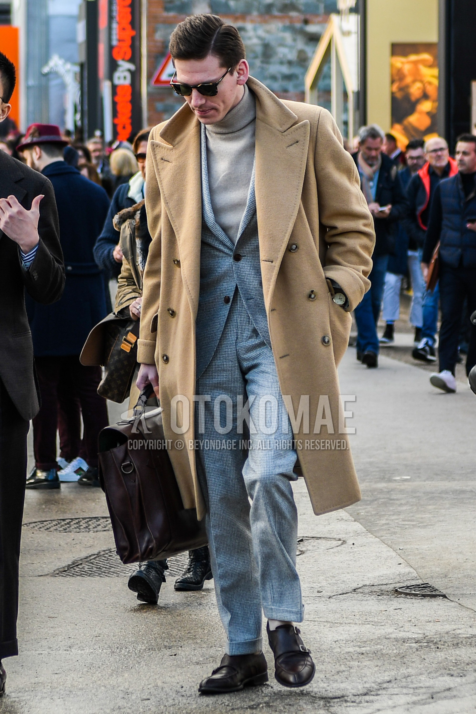 Men's winter outfit with plain sunglasses, brown plain chester coat, beige plain turtleneck knit, brown monk shoes leather shoes, brown plain briefcase/handbag, gray plain suit.