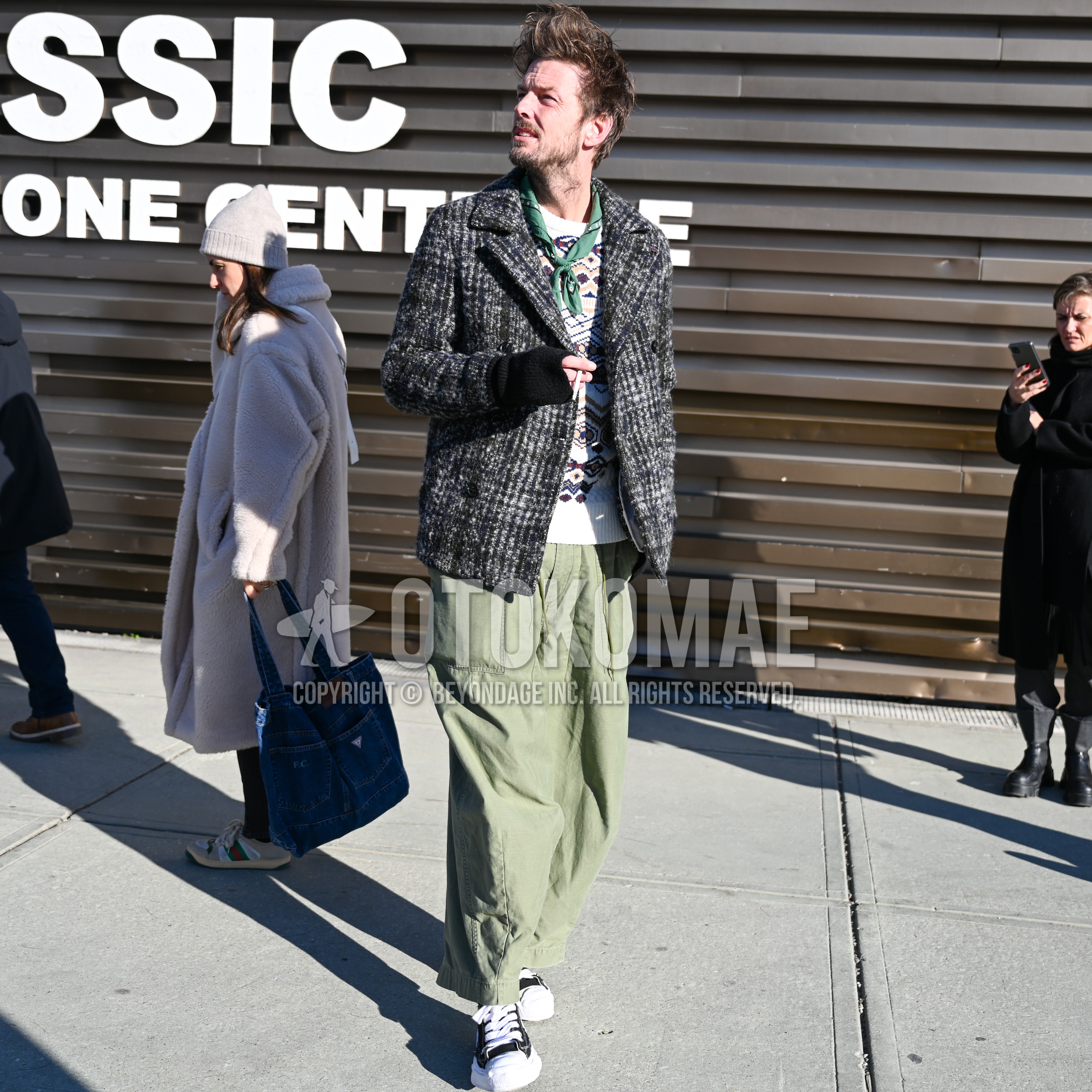 Men's spring autumn outfit with green plain bandana/neckerchief, gray check p coat, white brown beige graphic sweater, olive green plain cargo pants, black white low-cut sneakers.