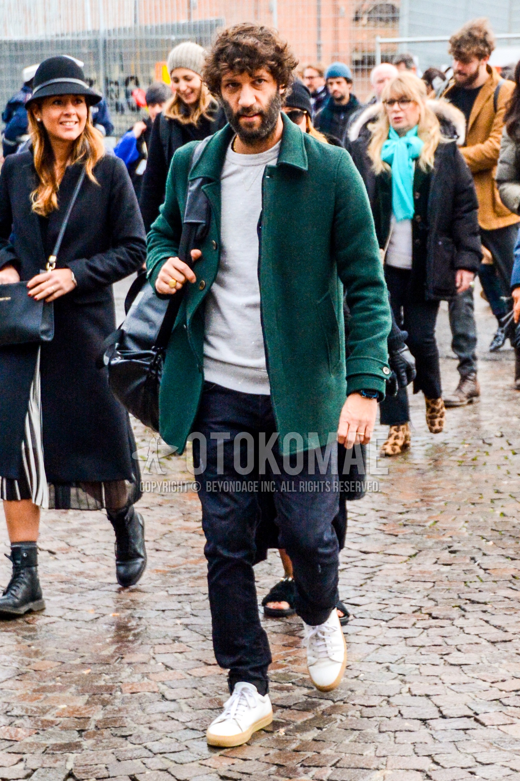 Men's autumn winter outfit with green plain stenkarrer coat, gray plain sweatshirt, black plain denim/jeans, white low-cut sneakers.