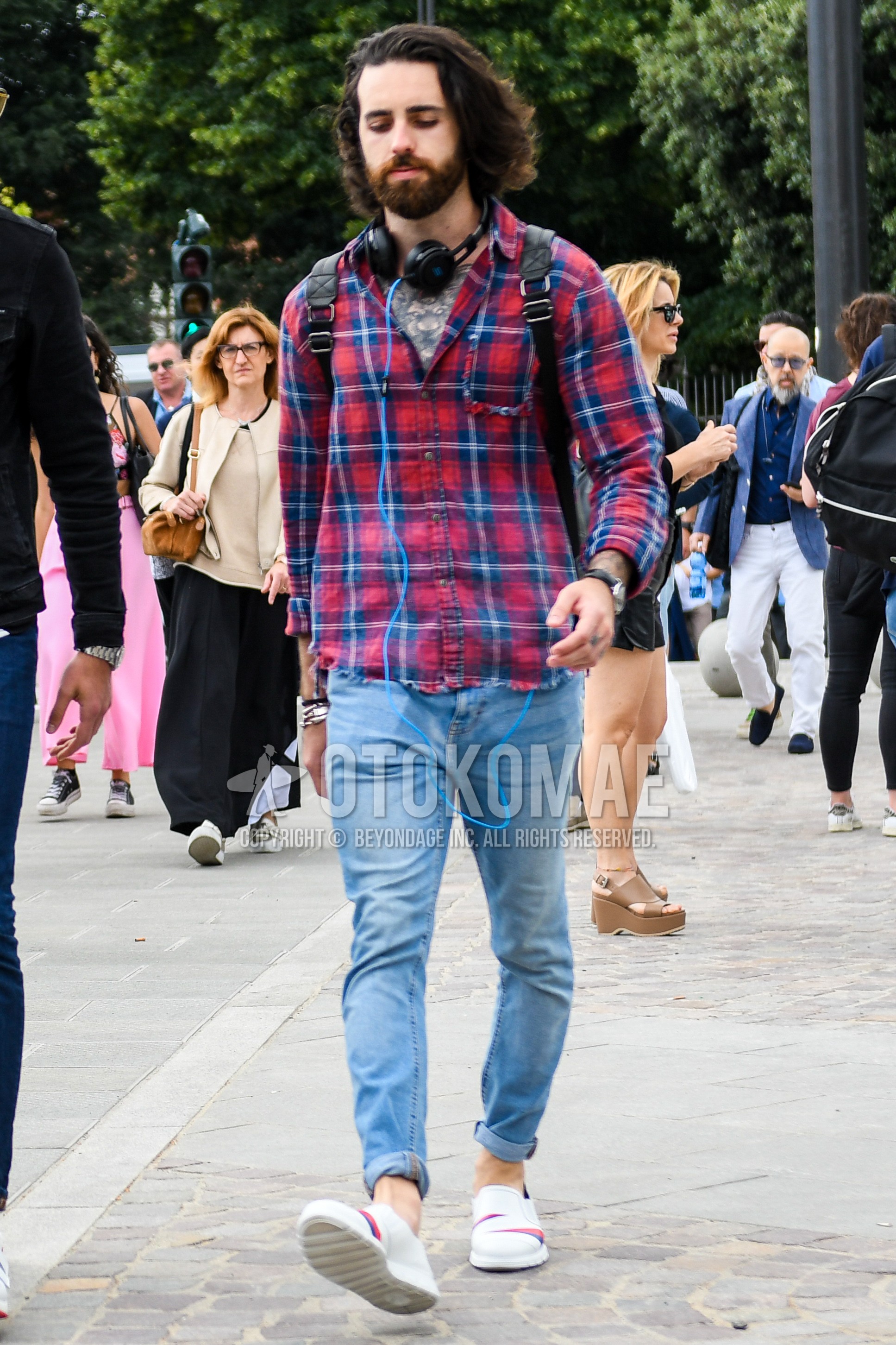 Men's spring summer autumn outfit with red blue check shirt, blue plain denim/jeans, white low-cut sneakers.