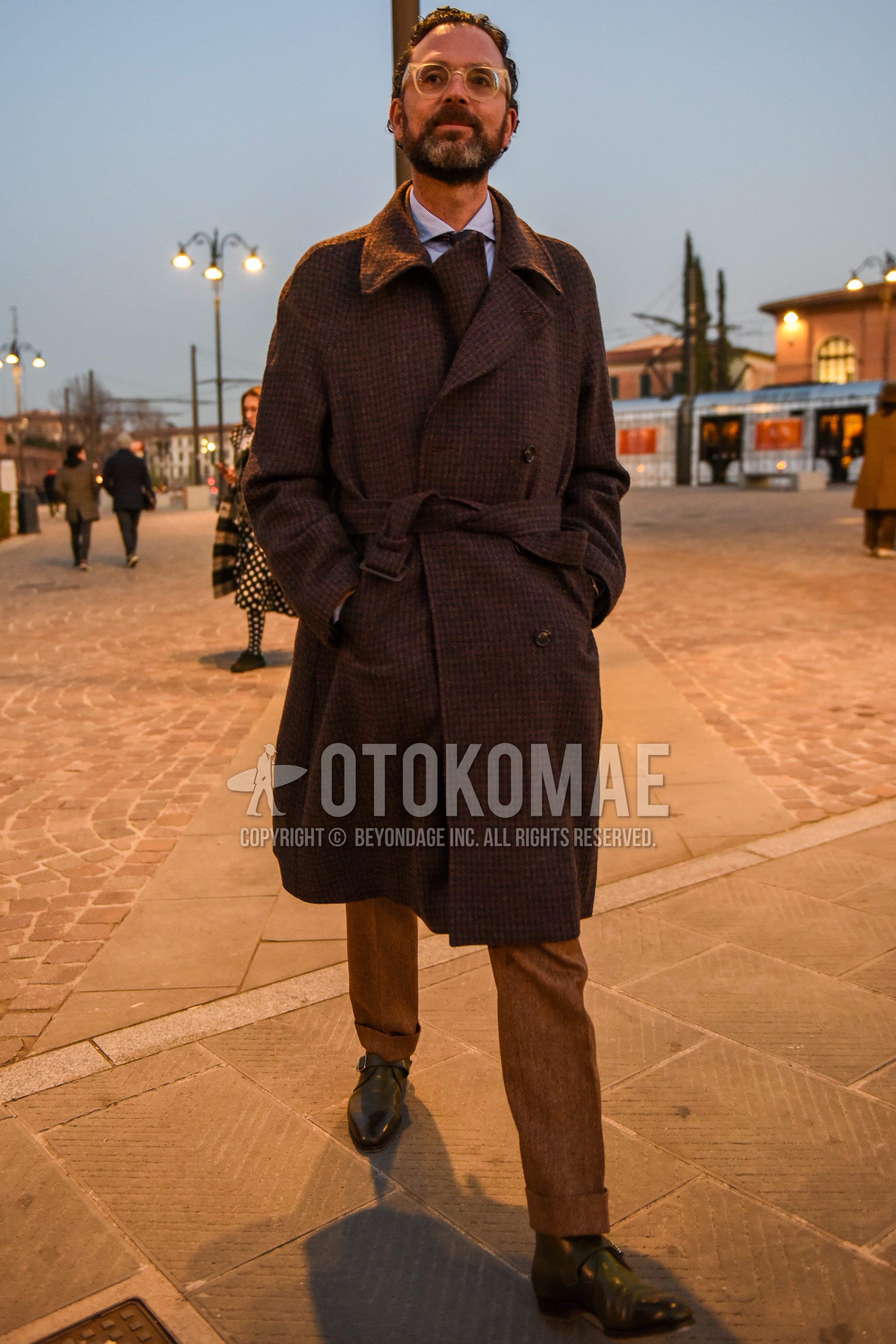 Men's autumn winter outfit with clear plain glasses, brown check trench coat, white plain shirt, brown plain slacks, brown plain toe leather shoes.