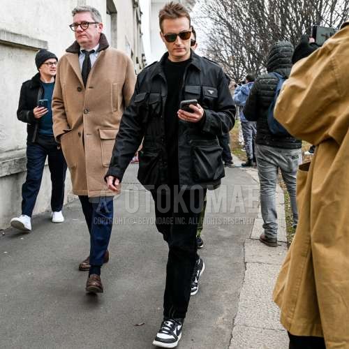 黒無地のサングラス、プラダの黒無地のミリタリージャケット(MA-1、M-65以外)、黒無地のセーター、黒無地の冬パンツ(コーデュロイ,ベロア)、ナイキの白・黒ローカットのスニーカーを合わせた秋冬のメンズコーデ・着こなし。