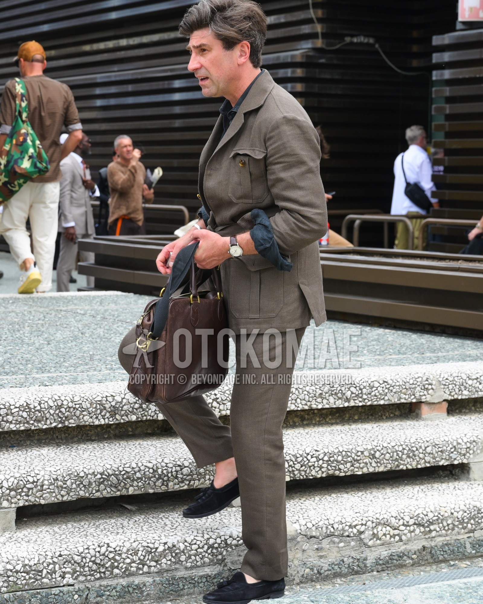 Men's spring summer autumn outfit with black plain shirt, black tassel loafers leather shoes, brown plain briefcase/handbag, brown plain casual setup.