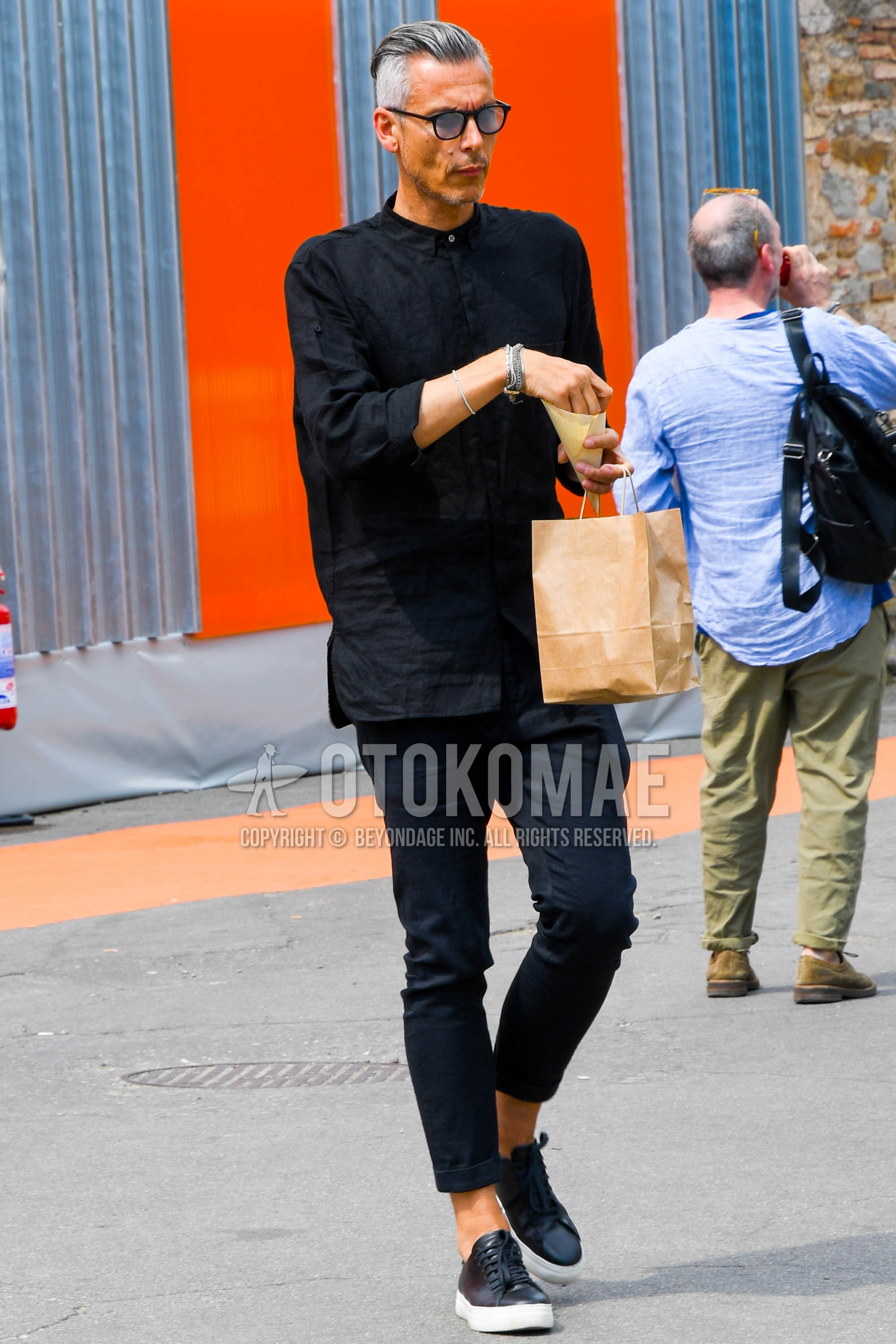 Men's spring summer outfit with black plain glasses, black plain shirt, black plain denim/jeans, black low-cut sneakers.