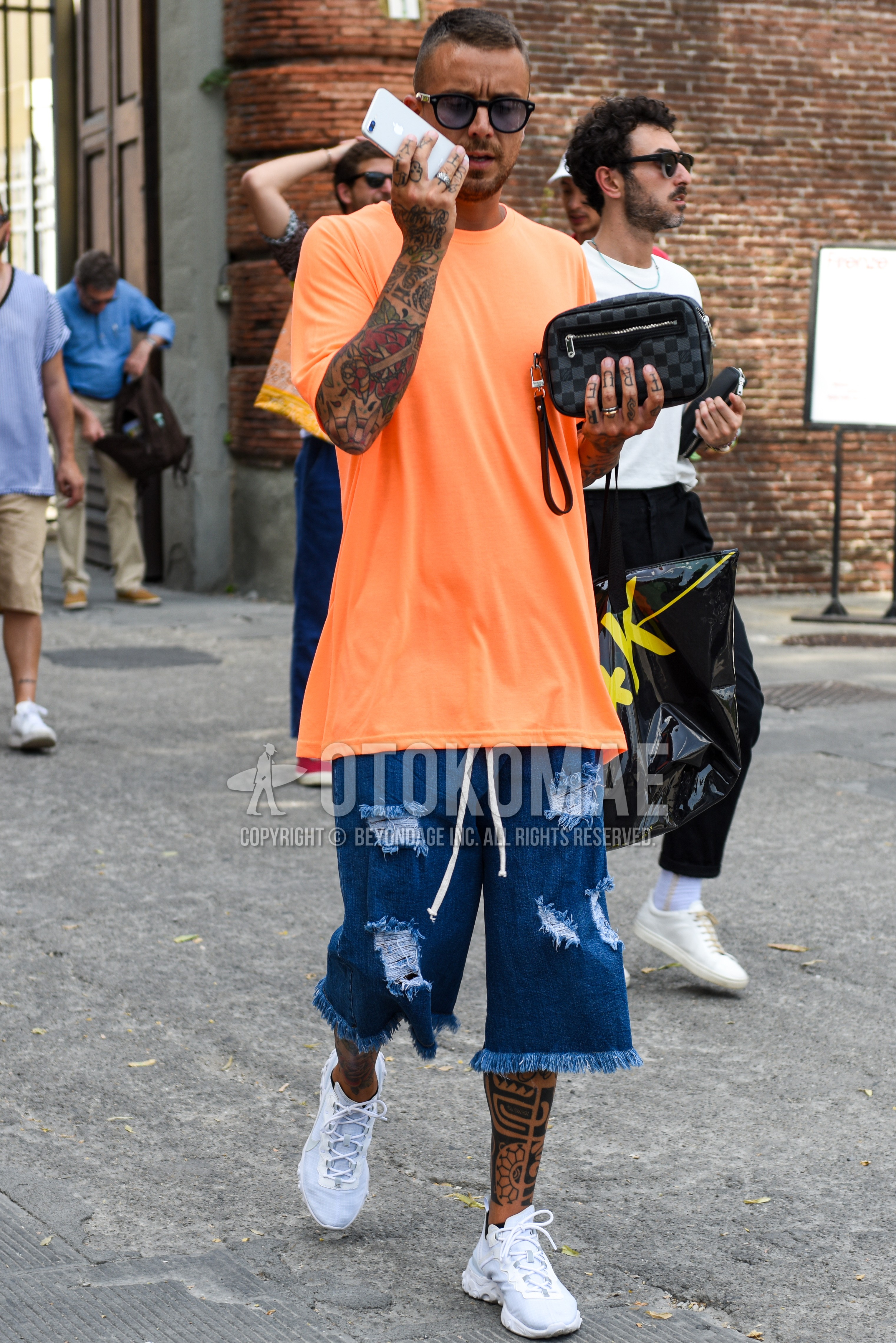 Men's summer outfit with black plain sunglasses, orange plain t-shirt, blue plain short pants, white low-cut sneakers, gray check clutch bag/second bag/drawstring bag.