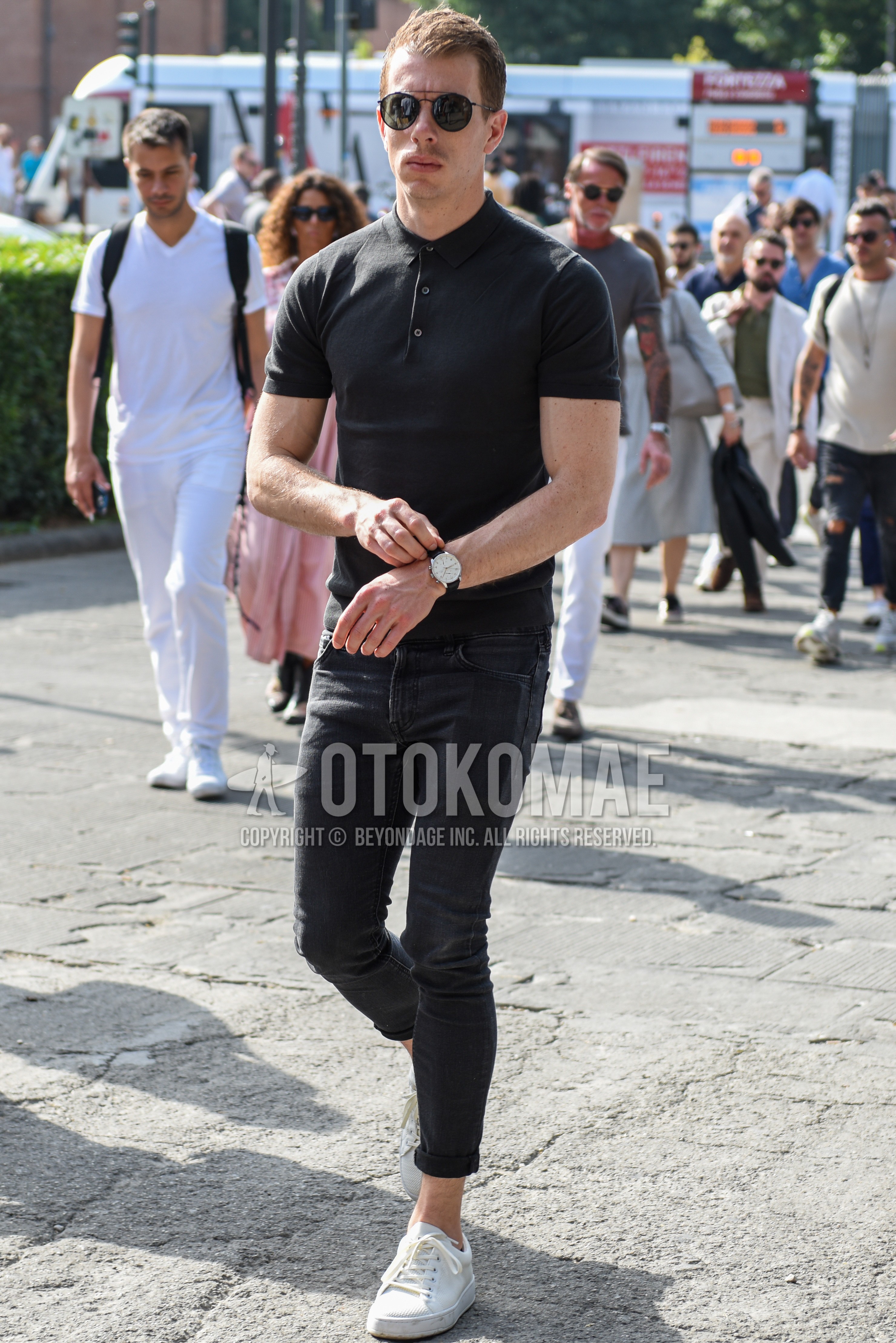 Men's summer outfit with black plain sunglasses, black plain polo shirt, dark gray plain denim/jeans, white low-cut sneakers.