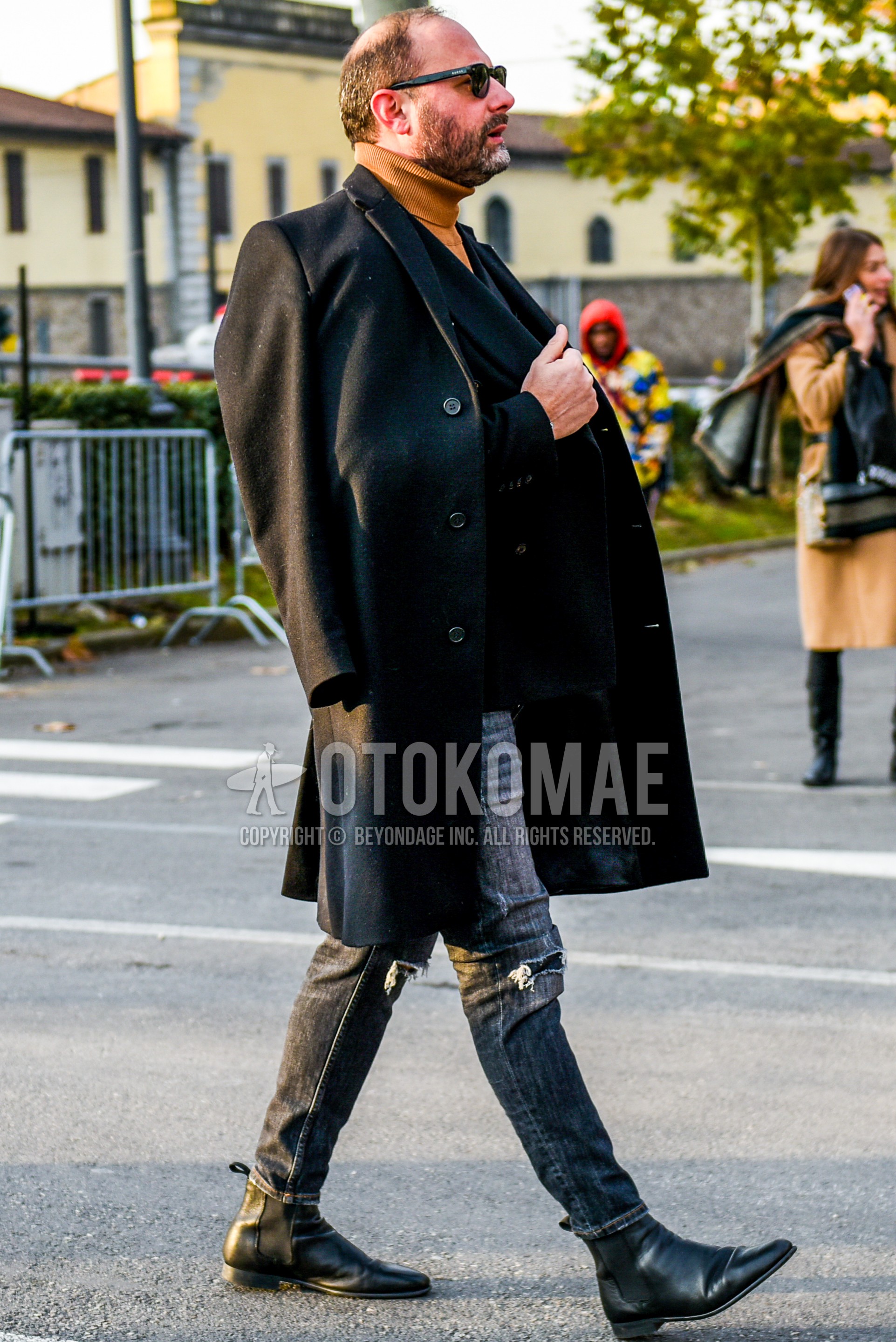 Men's autumn winter outfit with black plain sunglasses, black plain chester coat, navy plain tailored jacket, beige plain turtleneck knit, gray plain damaged jeans, black side-gore boots.
