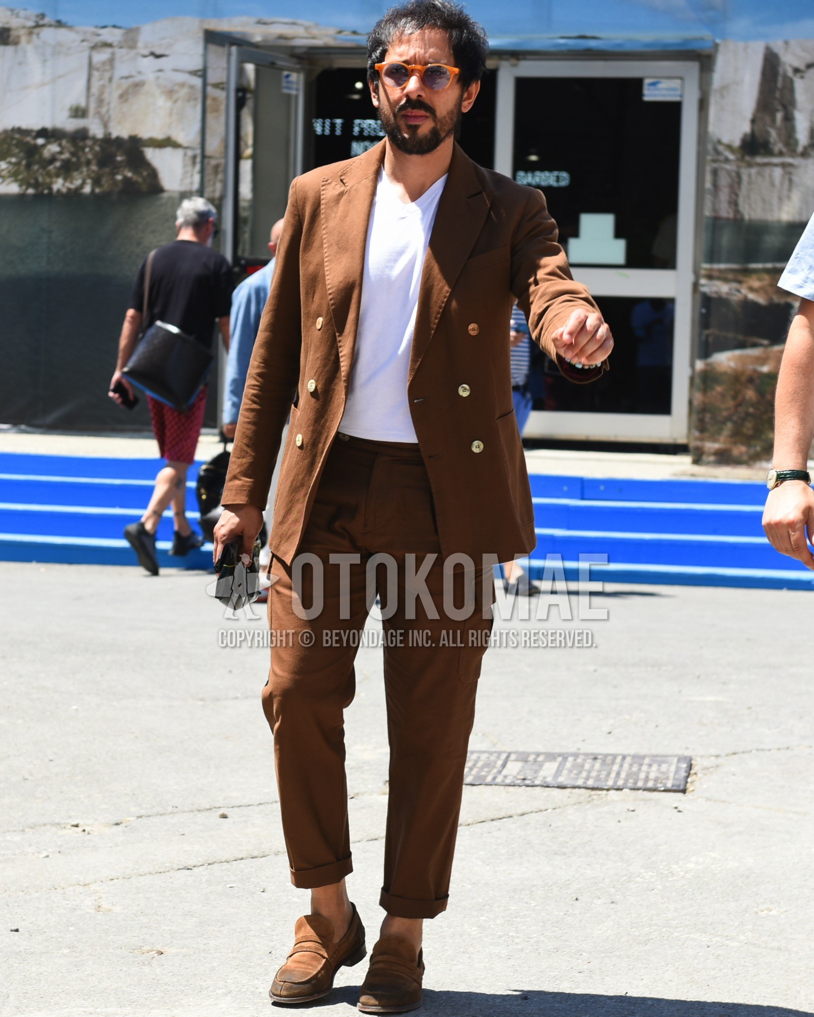 Men's spring summer outfit with orange plain sunglasses, white plain t-shirt, brown coin loafers leather shoes, brown plain suit.