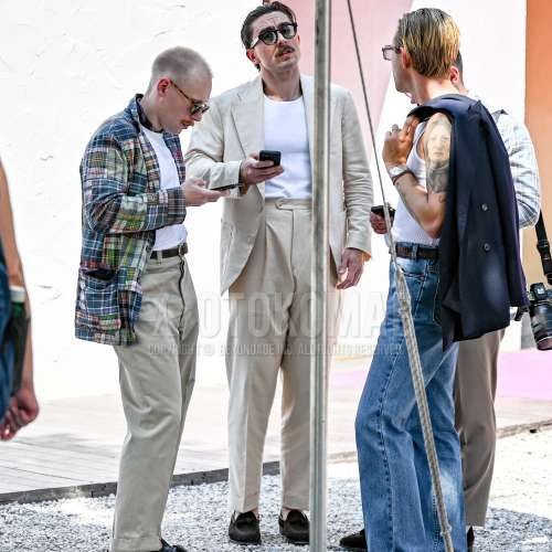 ウェリントンのブラウンべっ甲のサングラス、白無地のタンクトップ、白無地のベルトレスパンツ、ブラウンローファーの革靴、ブラウンスエードシューズの革靴、白無地のスーツを合わせた春夏のメンズコーデ・着こなし。