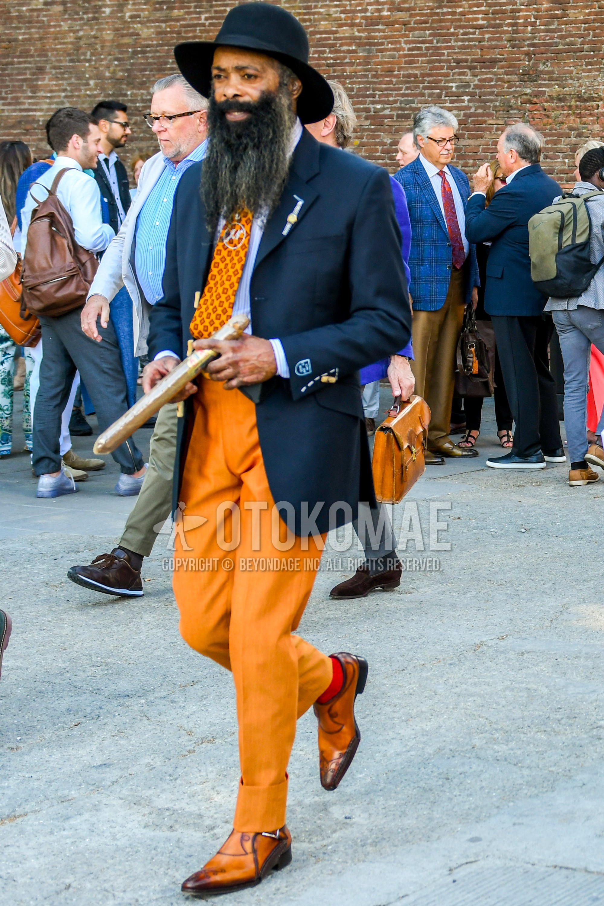 Men's spring summer autumn outfit with plain hat, navy plain tailored jacket, white plain shirt, orange plain slacks, brown  leather shoes, orange small crest necktie.