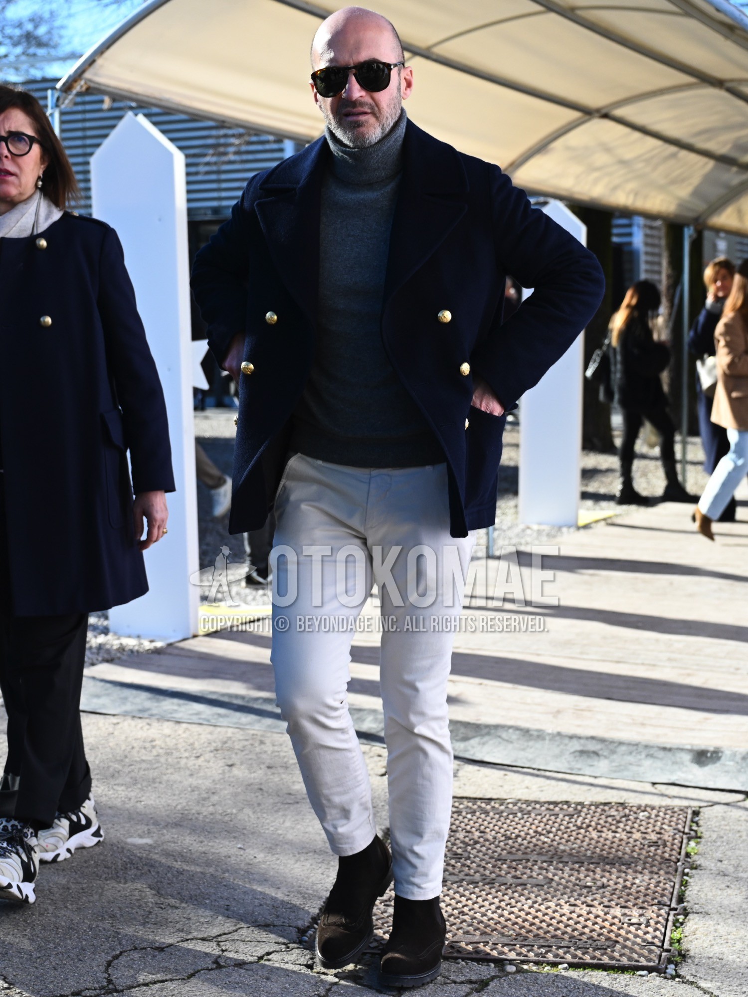 Men's spring autumn winter outfit with brown tortoiseshell sunglasses, navy plain ulster coat, gray plain turtleneck knit, white plain chinos, brown side-gore boots.