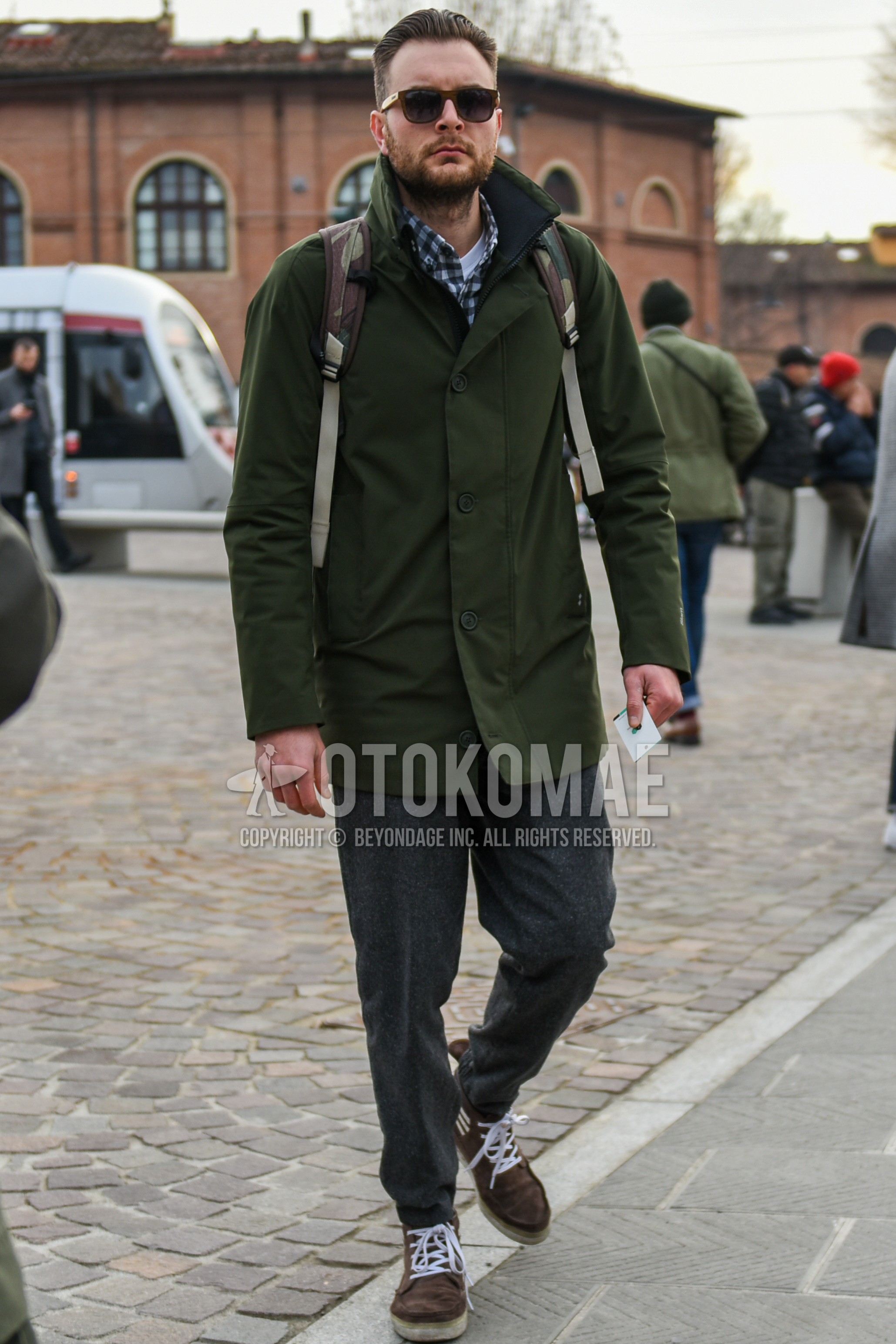 Men's autumn winter outfit with brown plain sunglasses, olive green plain stenkarrer coat, white gray check shirt, gray plain slacks, brown high-cut sneakers.