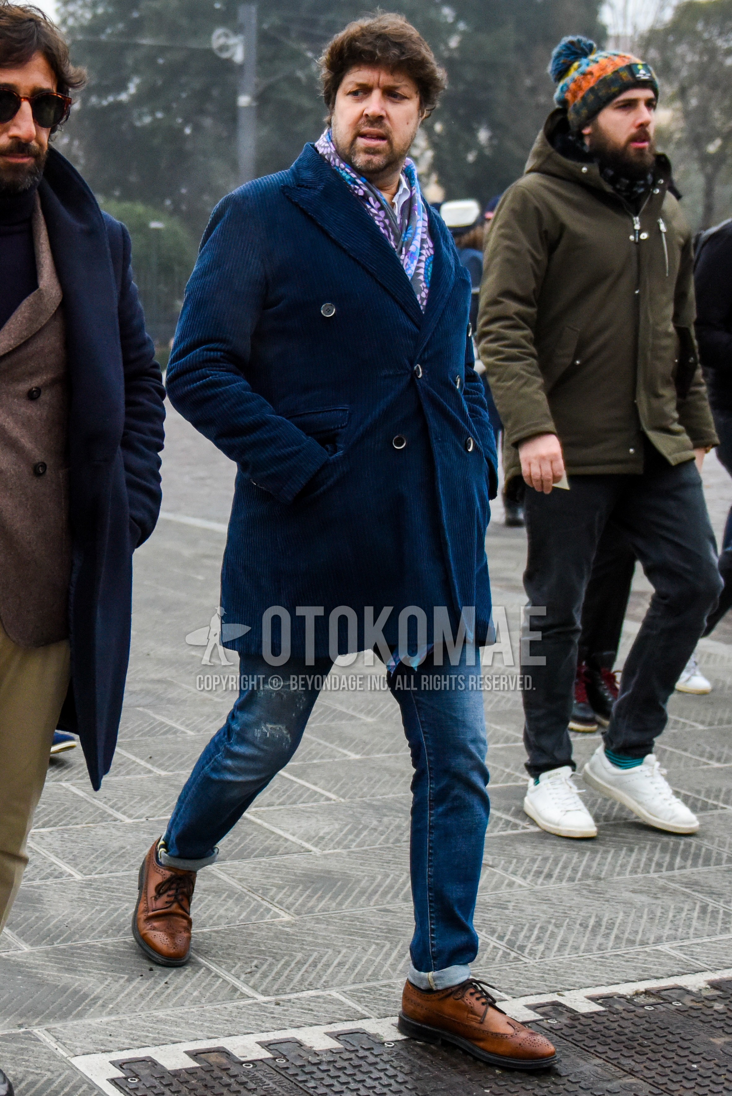 Men's winter outfit with multi-color scarf scarf, navy plain chester coat, blue plain damaged jeans, brown brogue shoes leather shoes.