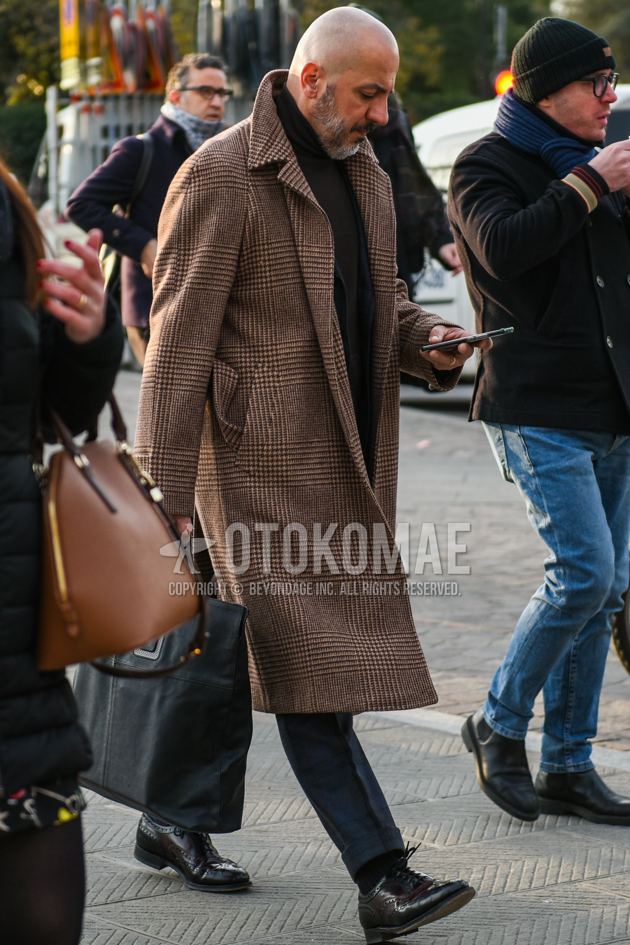 Men's autumn winter outfit with beige plain ulster coat, brown plain turtleneck knit, gray check slacks, navy plain socks, brown wing-tip shoes leather shoes.