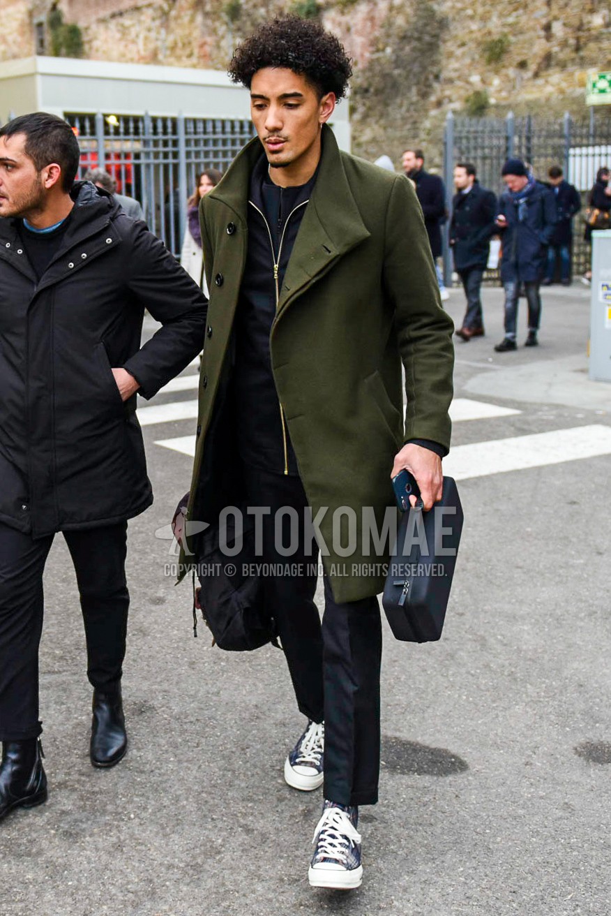 Men's winter outfit with olive green plain outerwear, black plain outerwear, navy check slacks, blue high-cut sneakers.