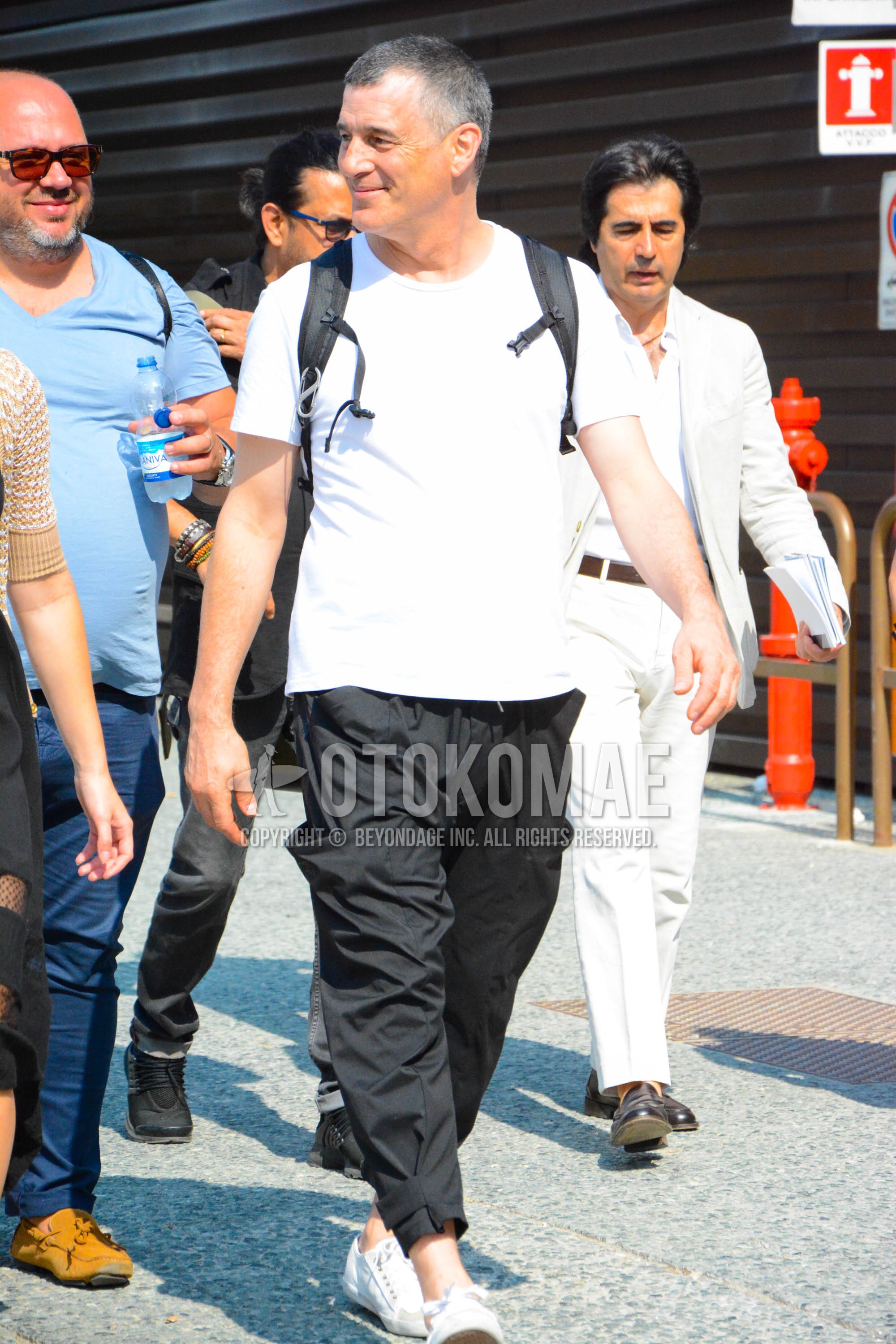 Men's spring summer outfit with white plain t-shirt, black plain cargo pants, white low-cut sneakers.