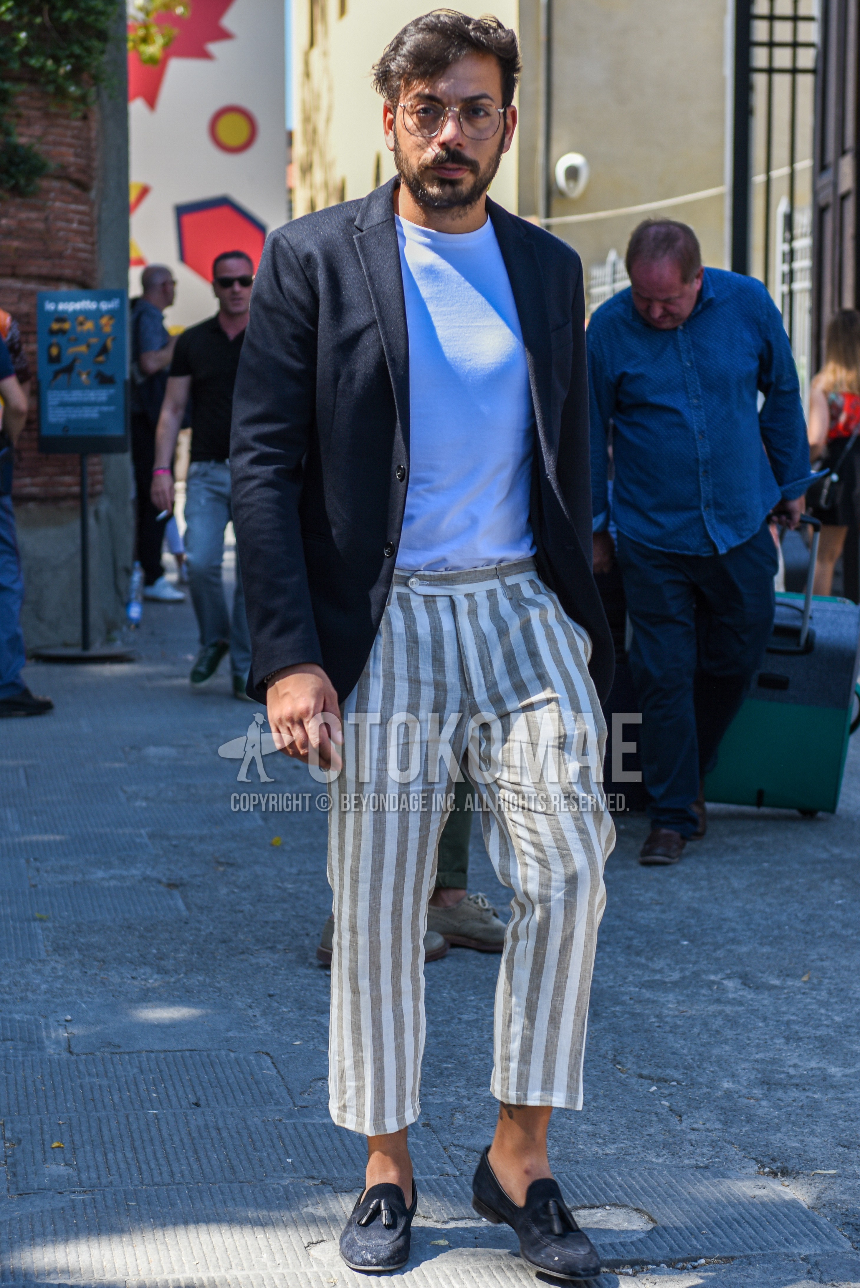 Men's spring summer autumn outfit with brown plain glasses, black plain tailored jacket, white plain t-shirt, white beige stripes cropped pants, navy tassel loafers leather shoes.