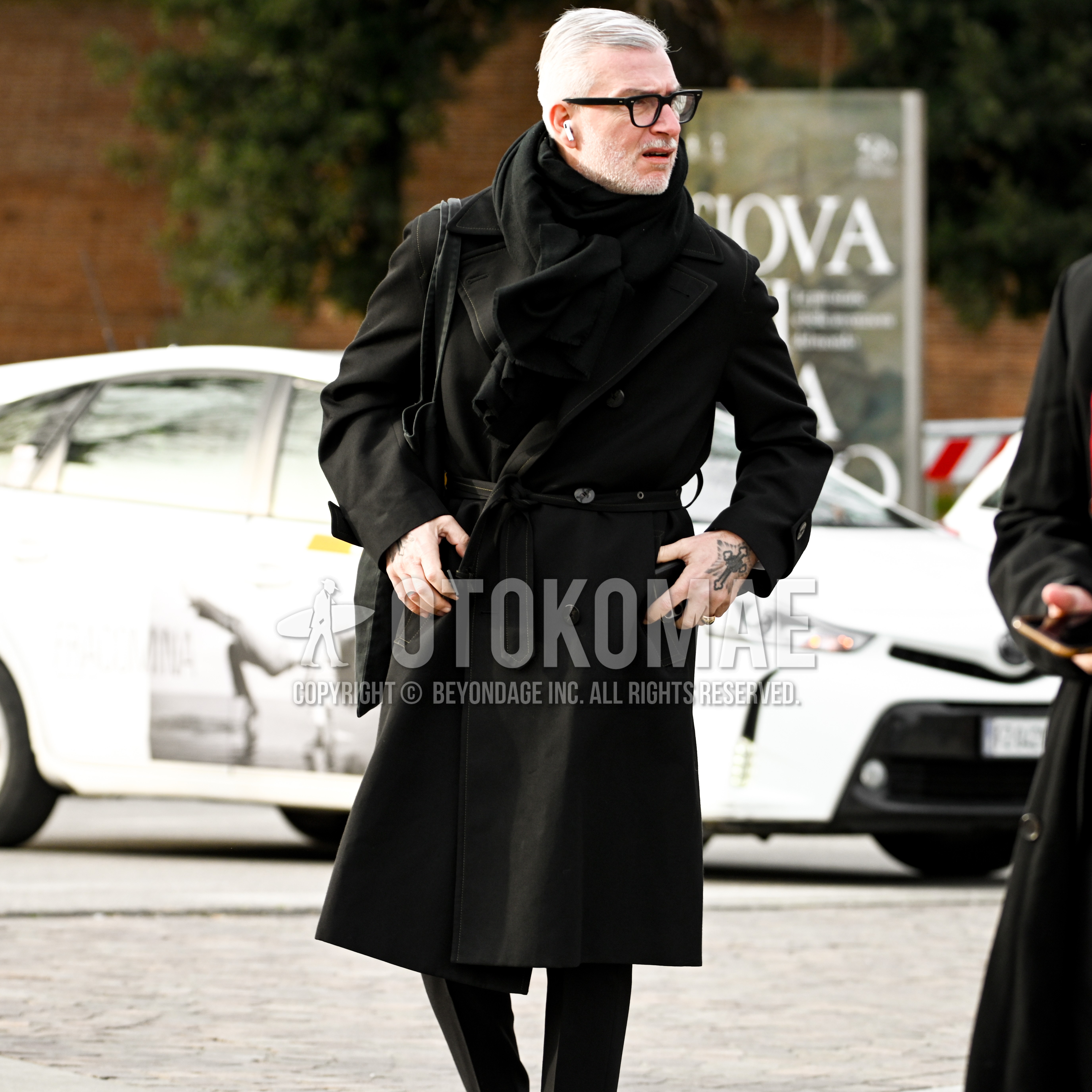 Men's autumn winter outfit with black plain glasses, black plain scarf, black plain trench coat, black plain slacks.