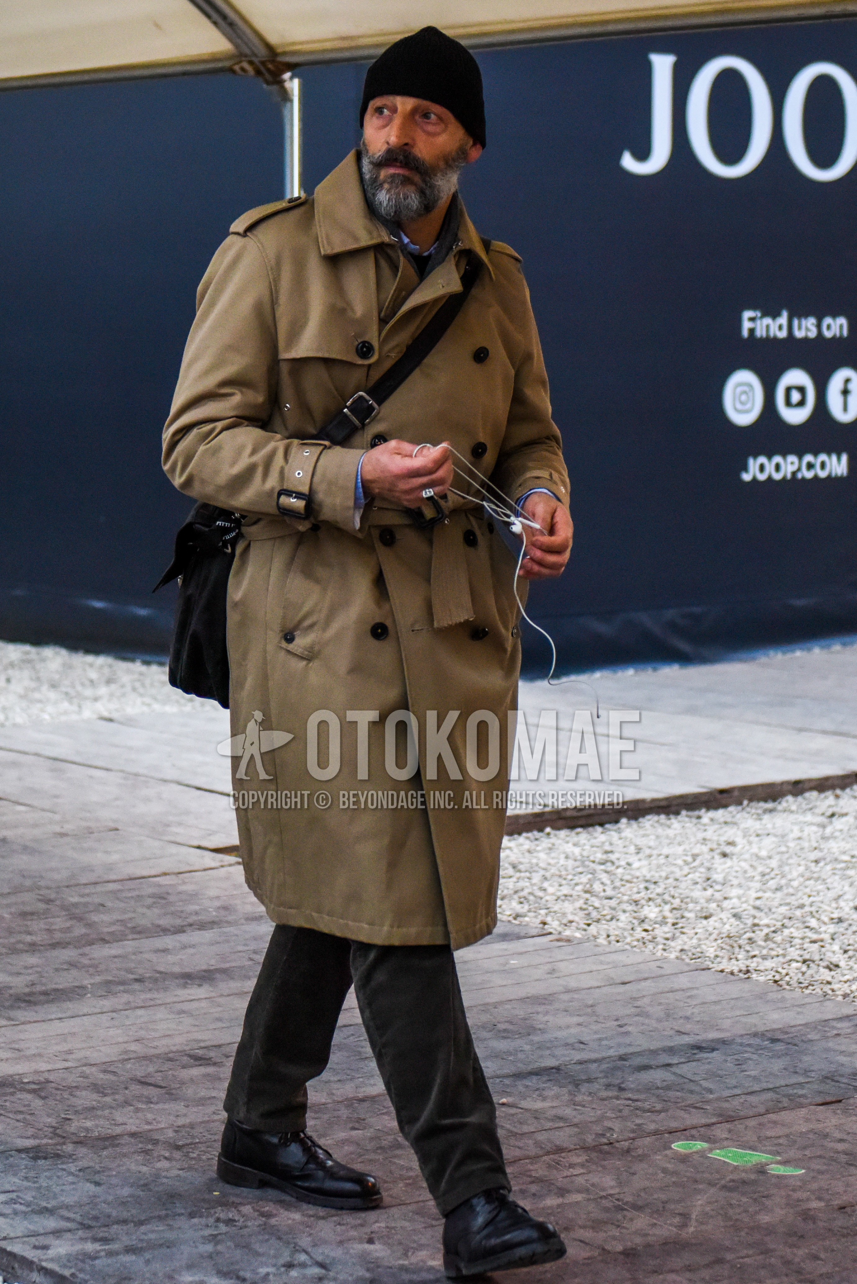Men's winter outfit with black plain knit cap, beige plain trench coat, dark gray plain winter pants (corduroy,velour), black straight-tip shoes leather shoes, black plain shoulder bag.