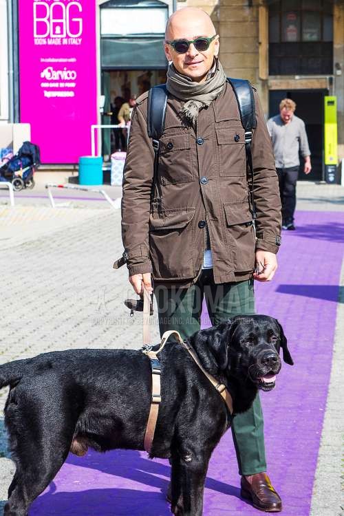 グリーン無地のサングラス、ベージュ無地のマフラー/ストール、ブラウン無地のM-65、白無地のシャツ、グリーン無地のスラックス、ブラウンコインローファーの革靴を合わせた秋冬のメンズコーデ・着こなし。