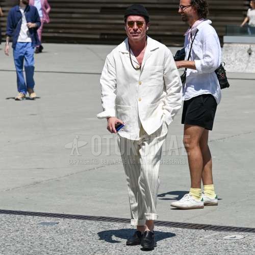 黒無地のキャップ、ゴールド無地のサングラス、開襟　オープンカラーの黒無地のシャツ、白ストライプのスラックス、黒ローファーの革靴を合わせた夏春のメンズコーデ・着こなし。