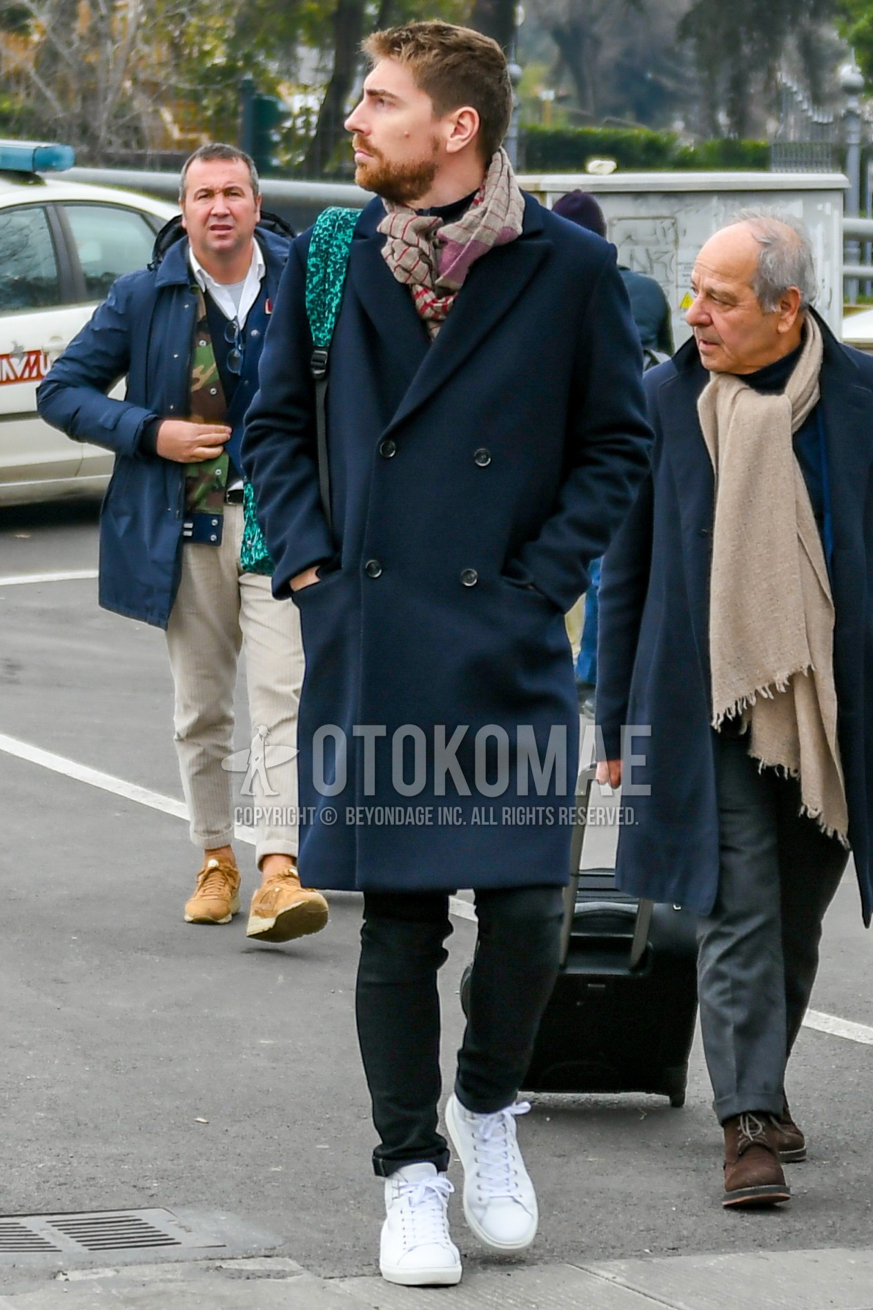 Men's winter outfit with brown scarf scarf, navy plain chester coat, black plain denim/jeans, white low-cut sneakers.