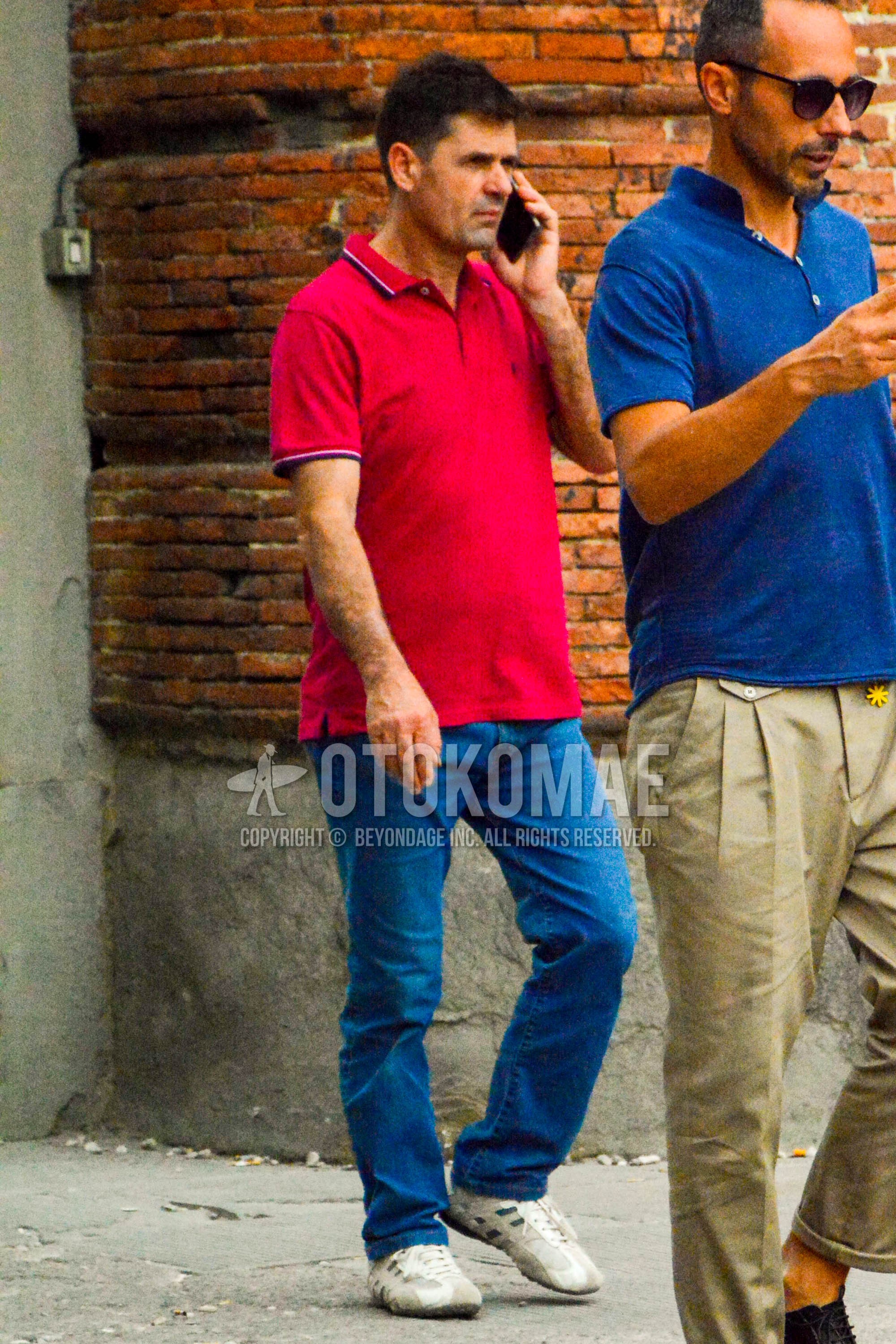 Men's summer outfit with red plain polo shirt, blue plain denim/jeans, white low-cut sneakers.