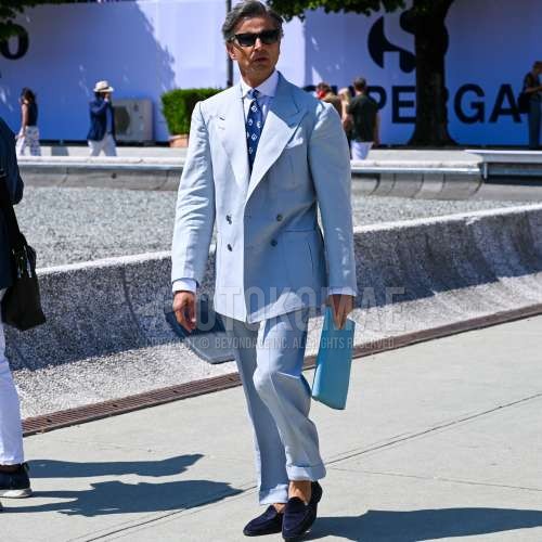 黒無地のサングラス、白無地のシャツ、ブルーローファーの革靴、ブルースエードシューズの革靴、水色無地のスーツ、ブルー小紋のネクタイを合わせた春夏のメンズコーデ・着こなし。