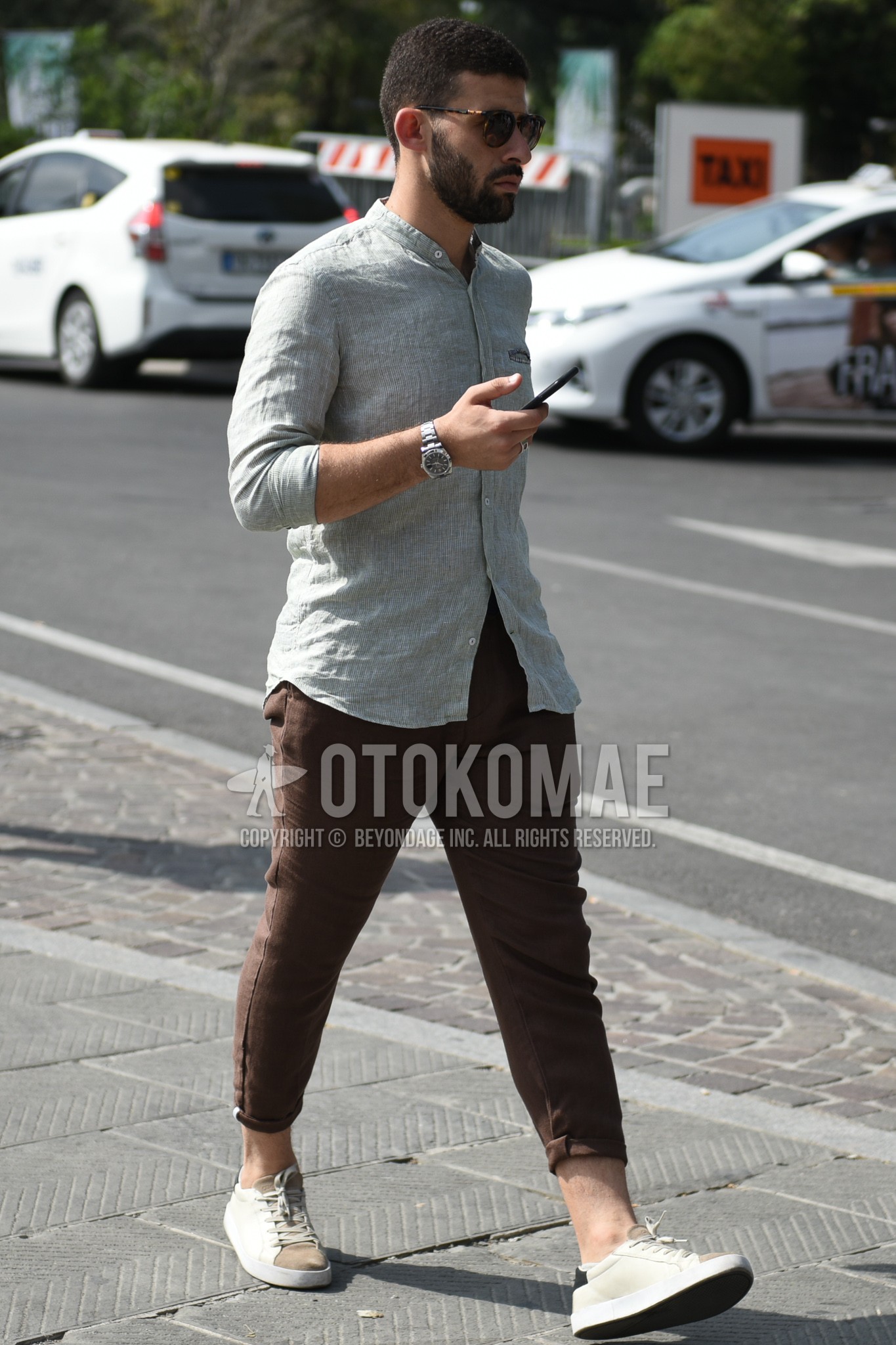 Men's summer outfit with brown tortoiseshell sunglasses, gray stripes shirt, brown plain chinos, beige brown low-cut sneakers.