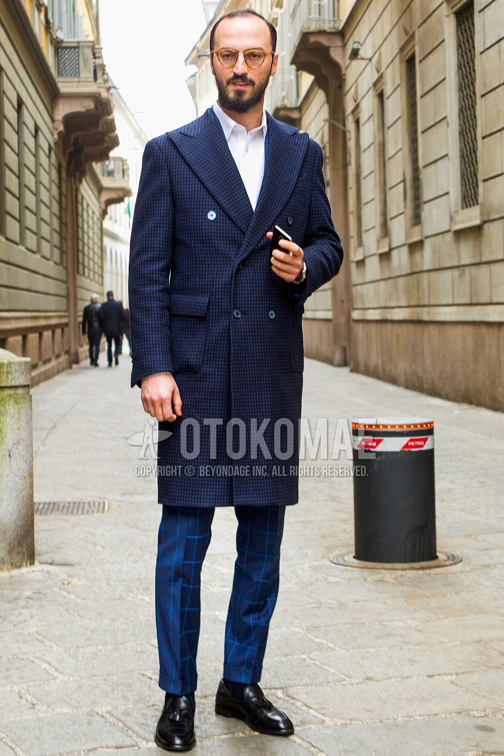 Men's autumn winter outfit with brown tortoiseshell glasses, navy check chester coat, white plain shirt, navy check slacks, black plain socks, black tassel loafers leather shoes.