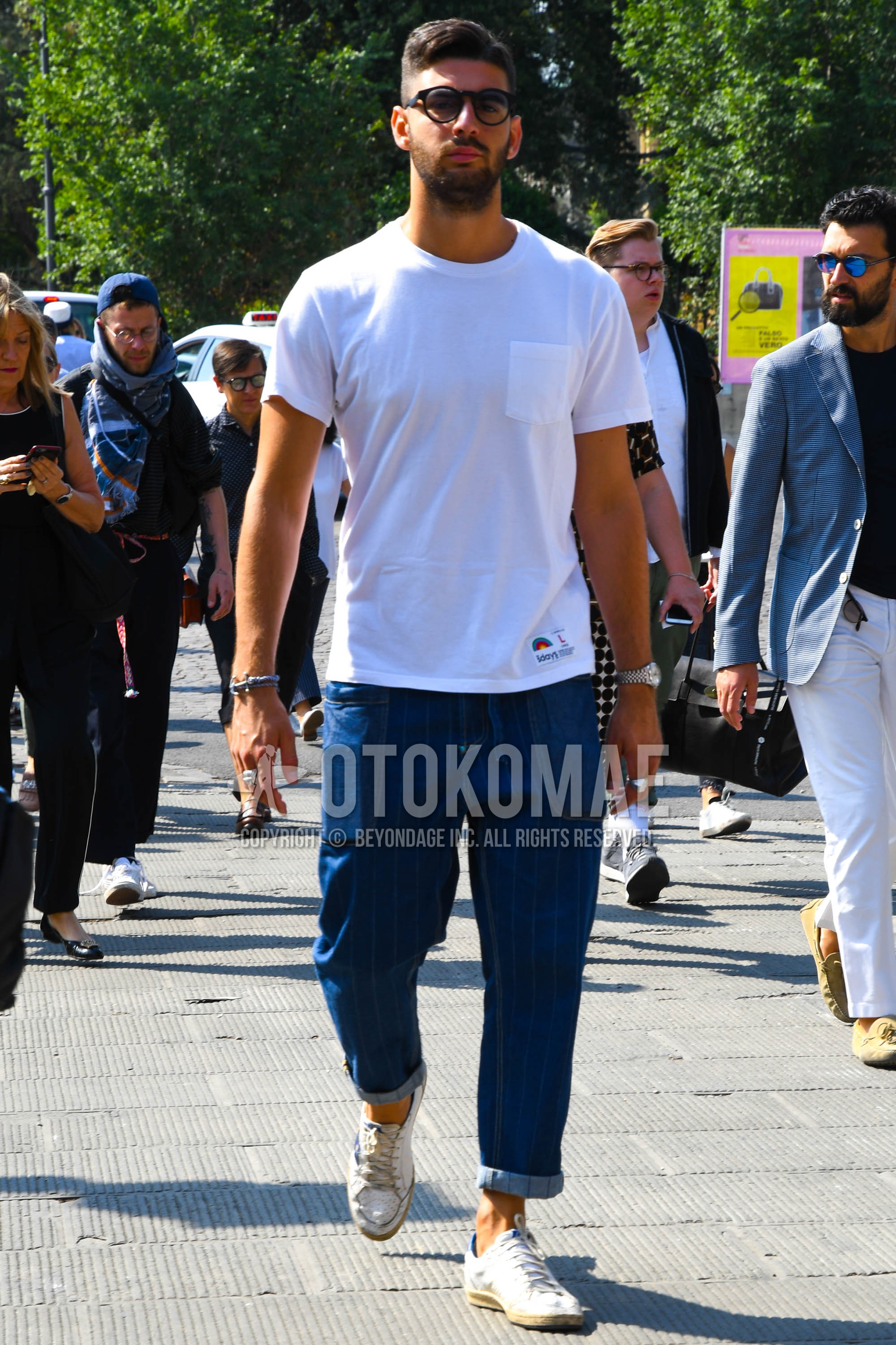 Men's summer outfit with plain sunglasses, white plain t-shirt, blue stripes easy pants, white low-cut sneakers.