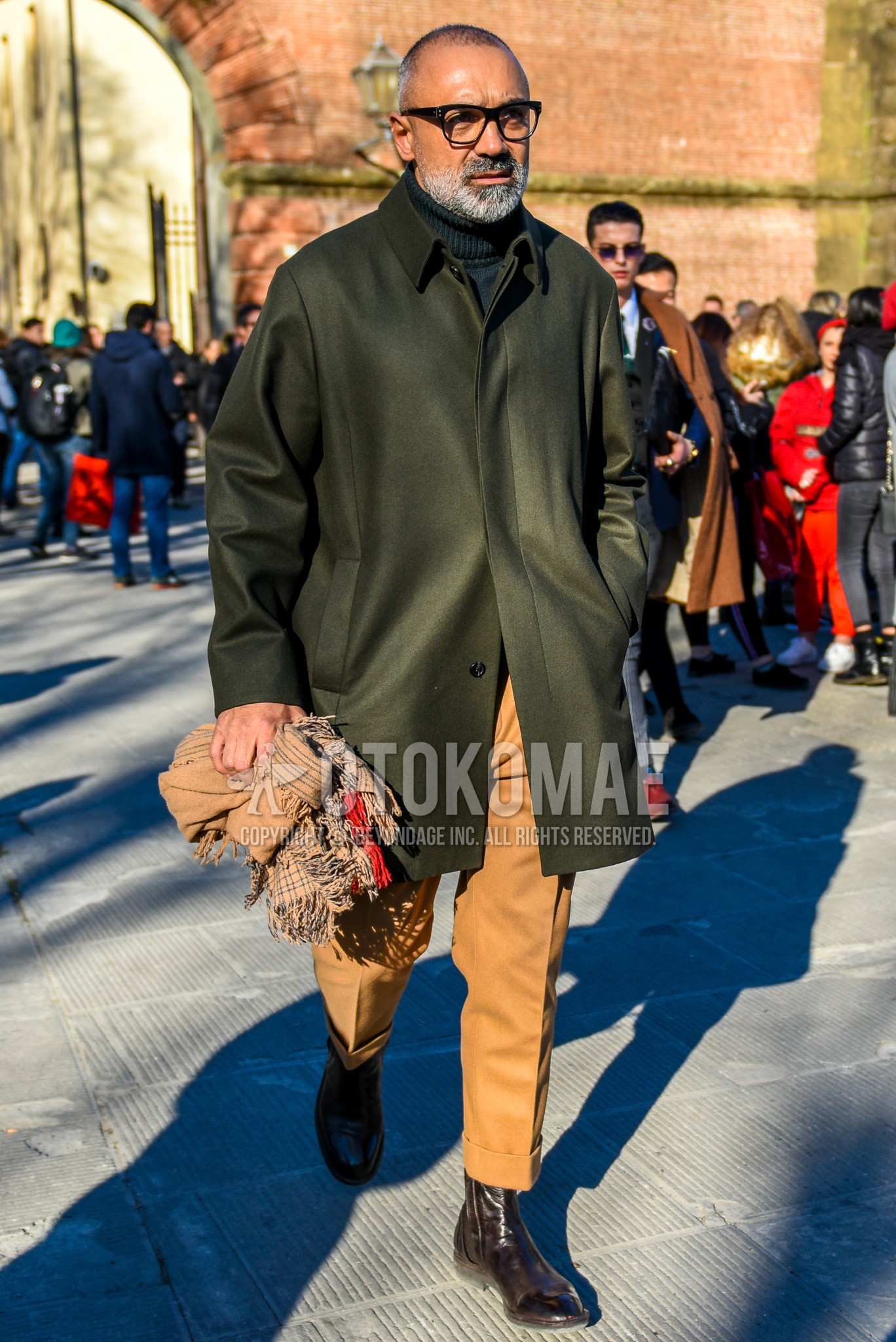Men's autumn winter outfit with black plain glasses, olive green plain stenkarrer coat, gray plain turtleneck knit, beige plain slacks, brown side-gore boots.