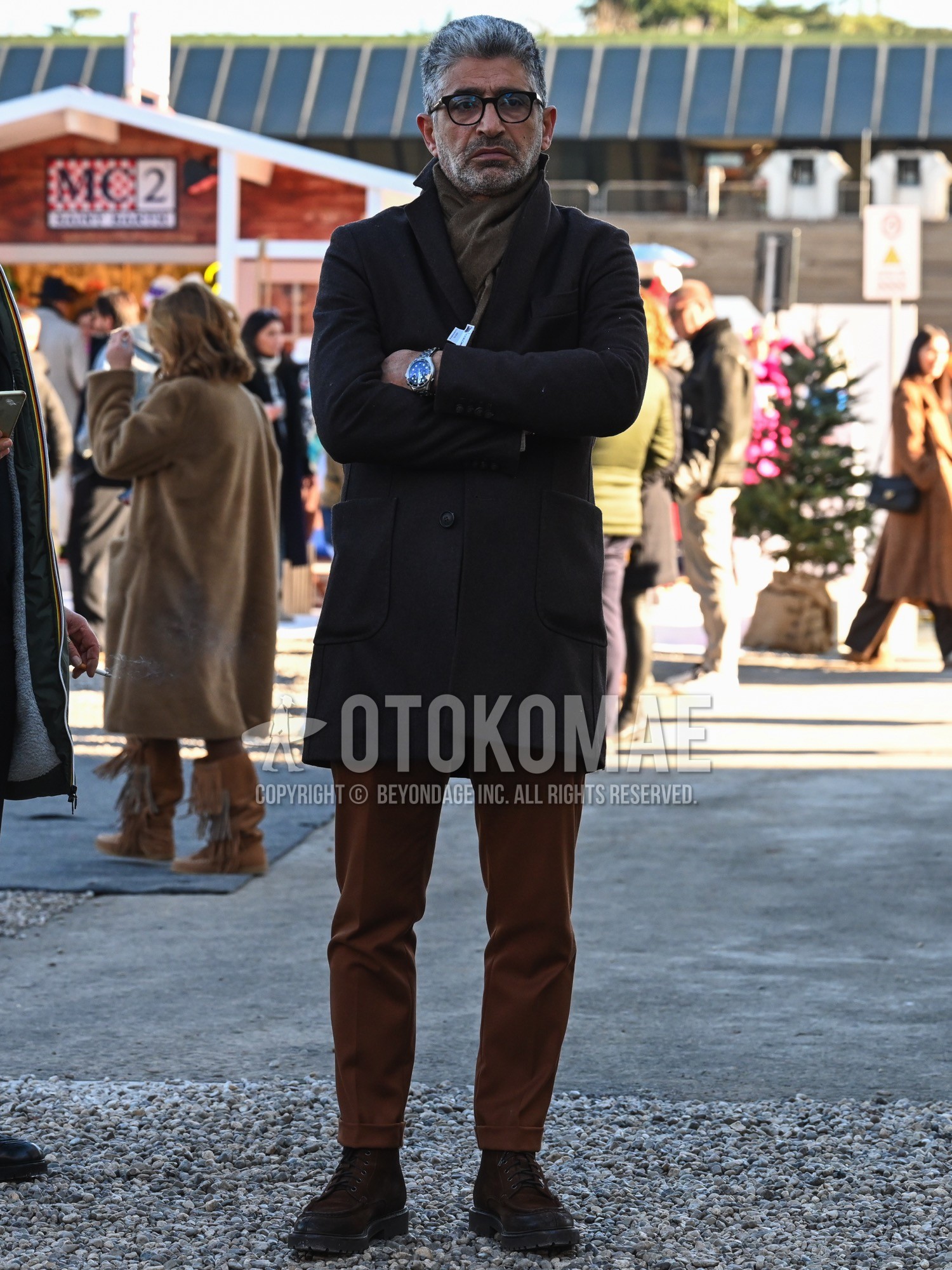 Men's autumn winter outfit with black plain glasses, brown plain scarf, brown plain chester coat, brown plain slacks, brown work boots.