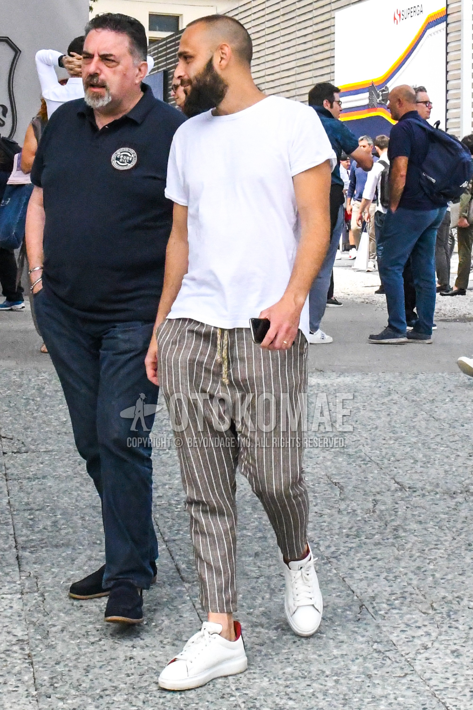 Men's summer outfit with white plain t-shirt, gray stripes ankle pants, white low-cut sneakers.