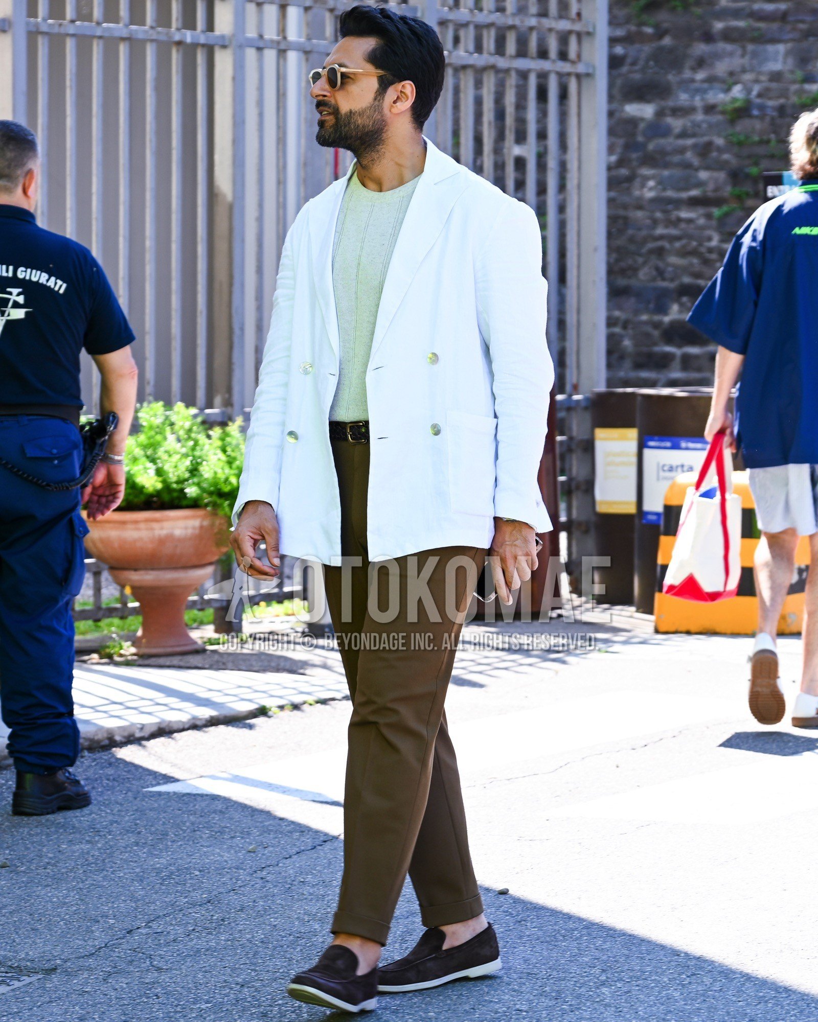 Men's spring summer autumn outfit with black plain sunglasses, white plain tailored jacket, green plain t-shirt, brown plain leather belt, brown plain chinos, brown slip-on sneakers.