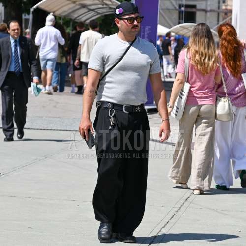 黒無地のジェットキャップ、黒無地のサングラス、グレー無地のTシャツ、黒無地のレザーベルト、黒無地のスラックス、黒無地のプリーツパンツ、黒の革靴を合わせた夏春のメンズコーデ・着こなし。