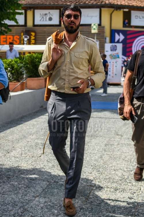 黒無地のサングラス、ベージュ無地のシャツ、グレー無地のベルトレスパンツ、ブラウンタッセルローファーの革靴を合わせた春夏秋のメンズコーデ・着こなし。