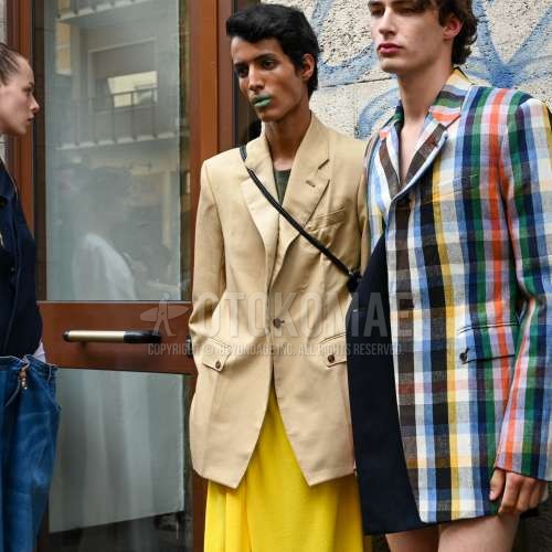 ベージュ無地のテーラードジャケット、グリーン無地のTシャツ、イエロー無地のボトムス、黒無地のショルダーバッグを合わせた夏春のメンズコーデ・着こなし。