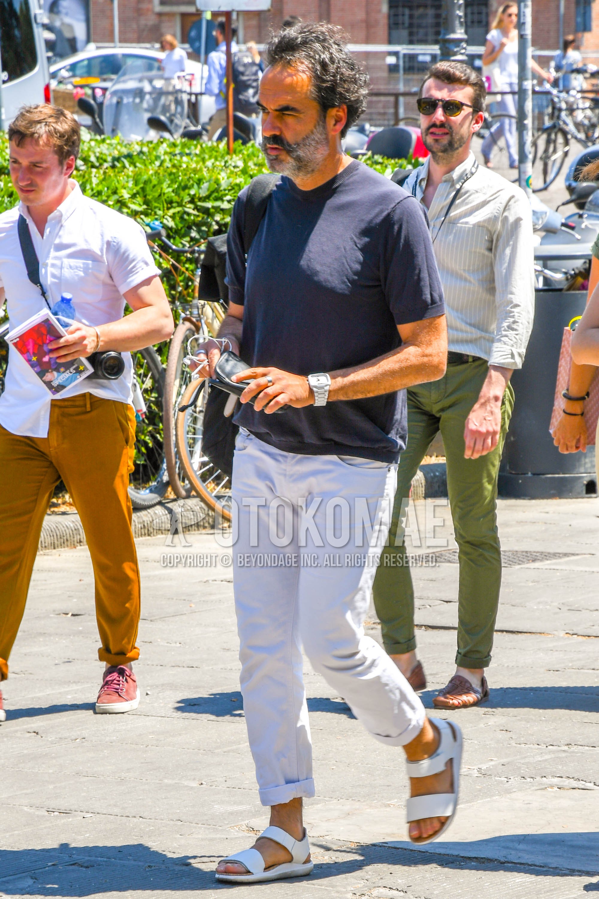 Men's summer outfit with navy plain t-shirt, white plain denim/jeans, white leather sandals.