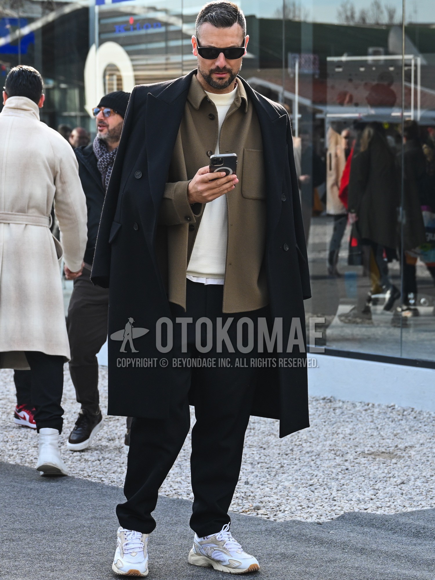 Men's autumn winter outfit with black plain sunglasses, brown plain coverall, black plain chester coat, white plain sweater, black plain slacks, white low-cut sneakers.