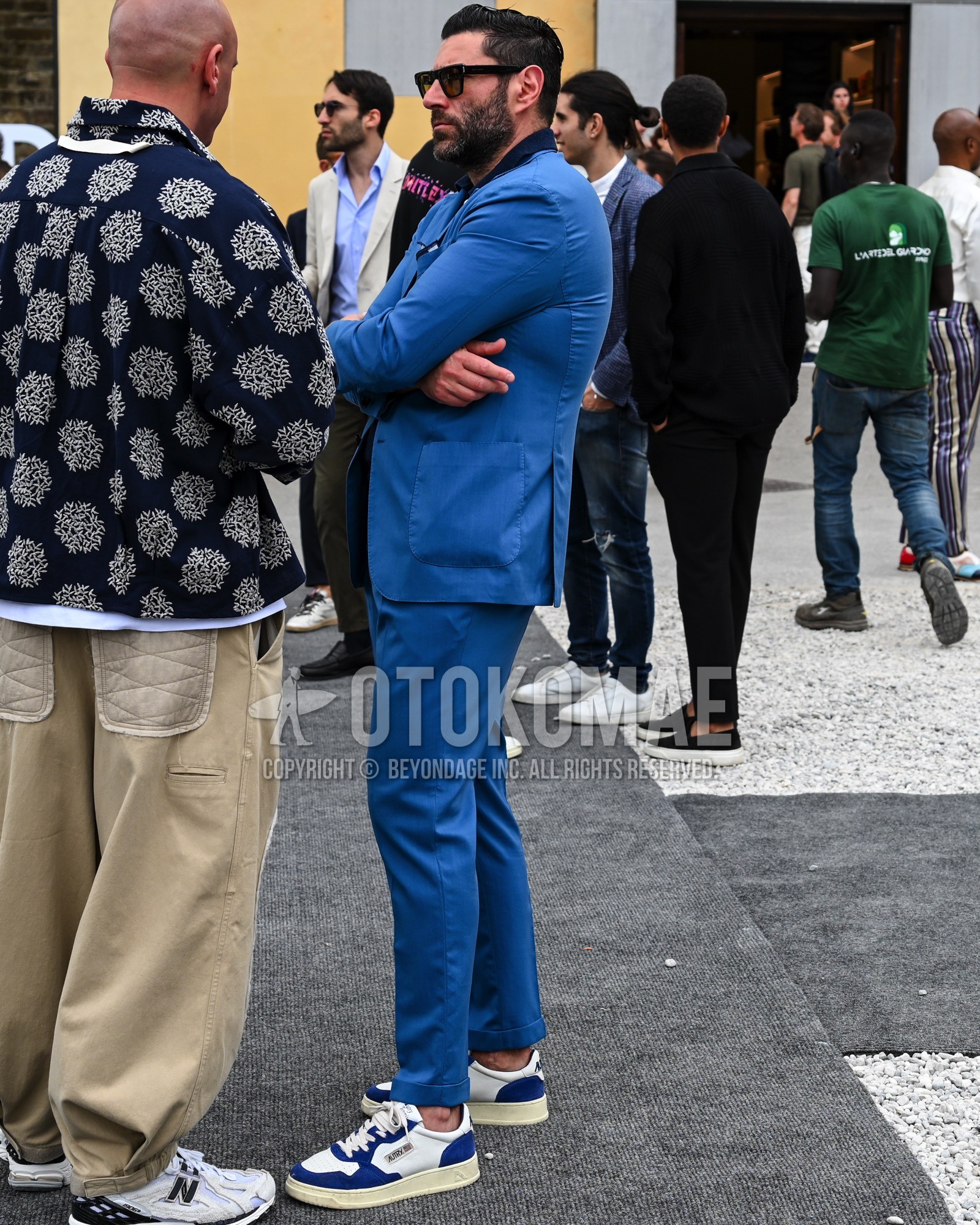 Men's spring summer autumn outfit with black plain sunglasses, navy plain shirt, blue white low-cut sneakers, blue plain suit.
