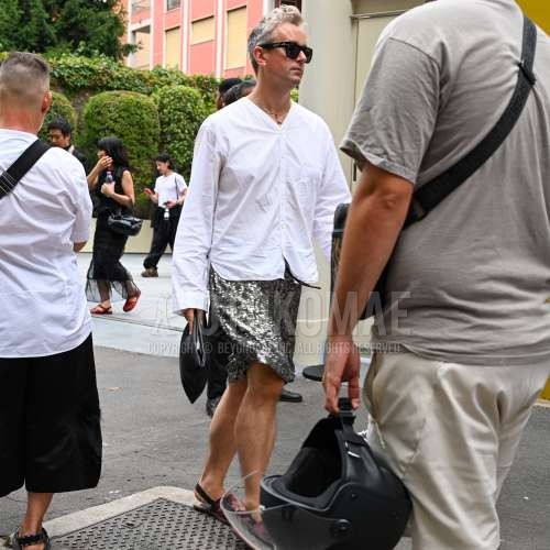 ペルソーるの黒無地のサングラス、ノーカラーの白無地のシャツ、シルバーボトムスのショートパンツ、パープルサンダル、レザーの黒無地のブリーフケース/ハンドバッグを合わせた夏春のメンズコーデ・着こなし。