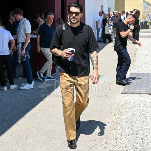 黒べっ甲のサングラス、黒無地のTシャツ、ベージュ無地のチノパン、ベージュ無地のプリーツパンツ、ベージュ無地のスラックス、黒ローファーの革靴、黒無地のバックパックを合わせた春夏のメンズコーデ・着こなし。