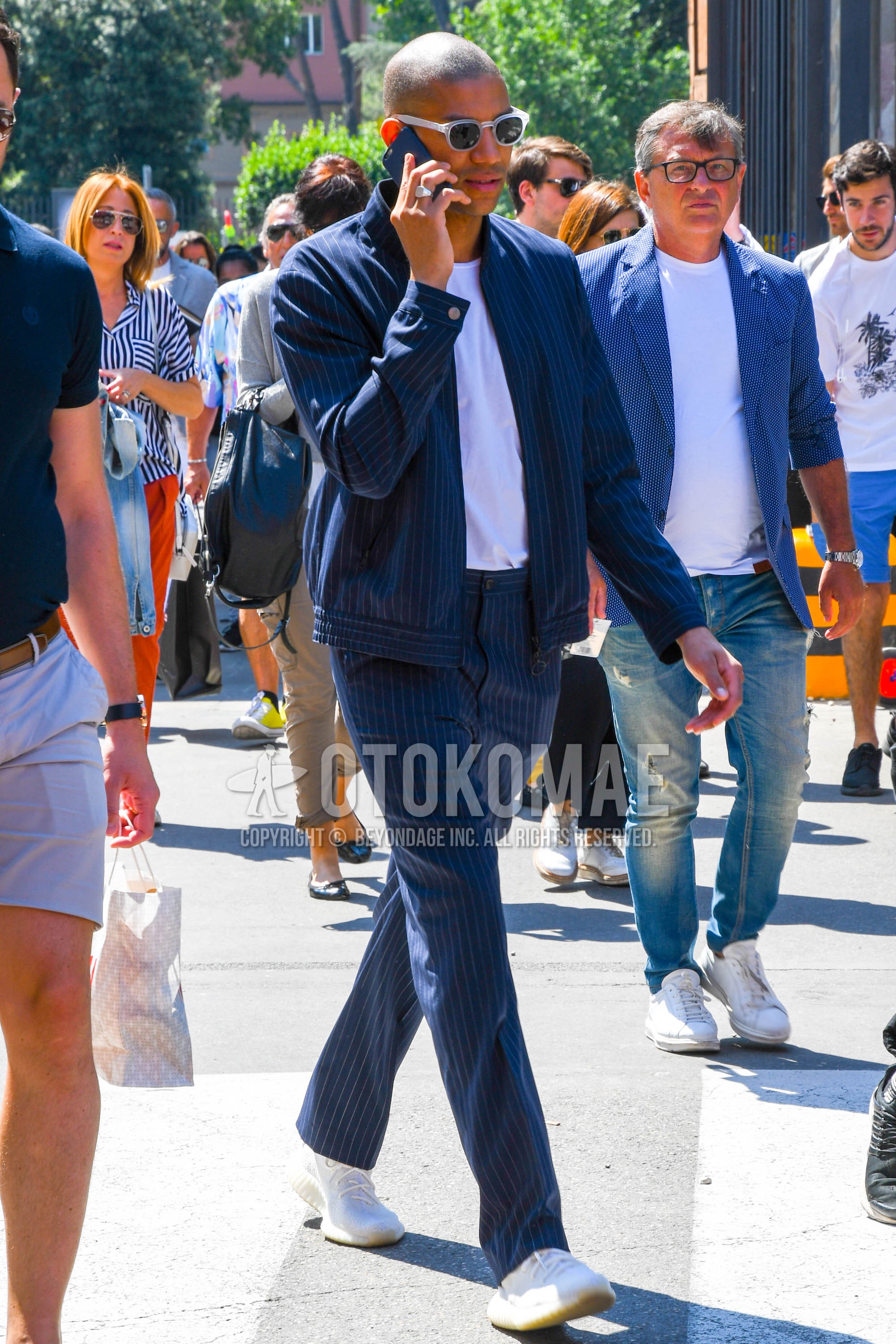 Men's spring summer autumn outfit with plain sunglasses, navy stripes outerwear, navy stripes slacks, white low-cut sneakers.