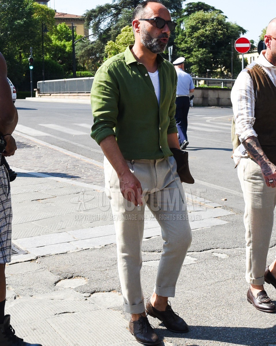 Men's spring summer outfit with black plain sunglasses, green plain shirt, white plain tank top, white plain slacks, brown plain toe leather shoes.