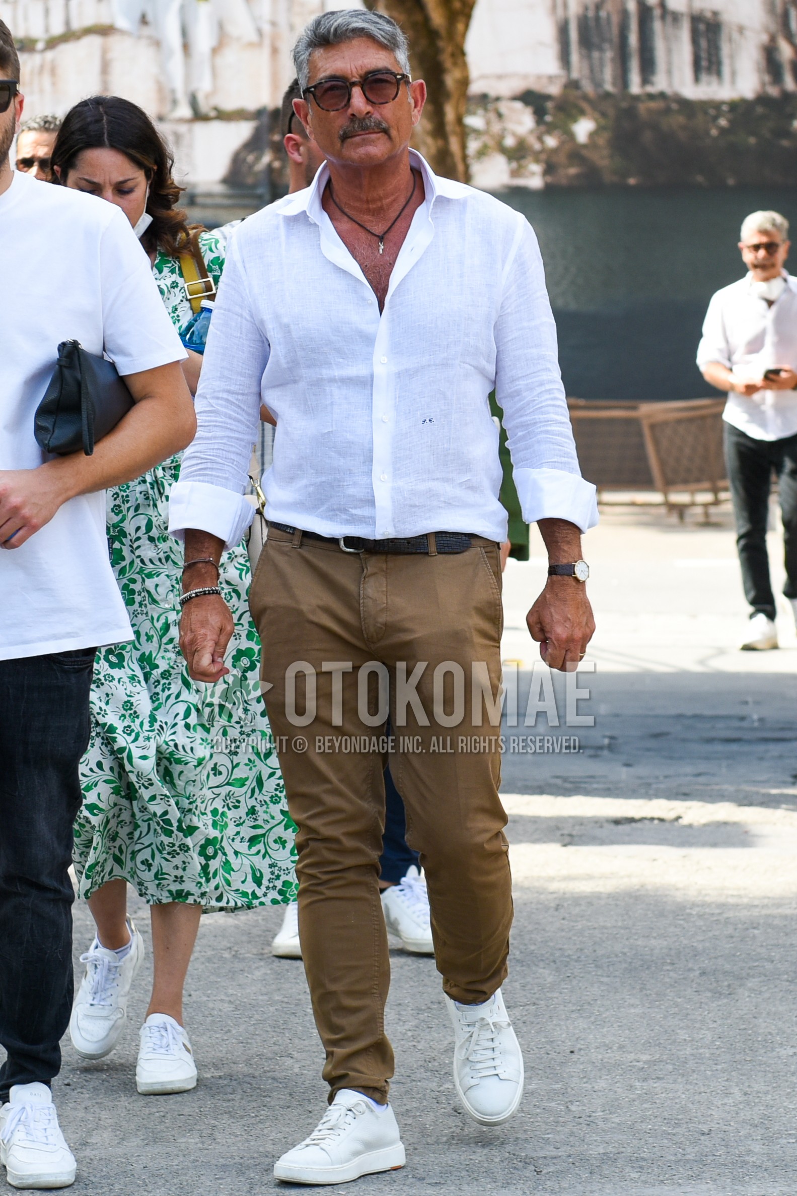 Men's spring summer outfit with brown tortoiseshell sunglasses, white plain shirt, brown plain leather belt, beige plain chinos, white low-cut sneakers.