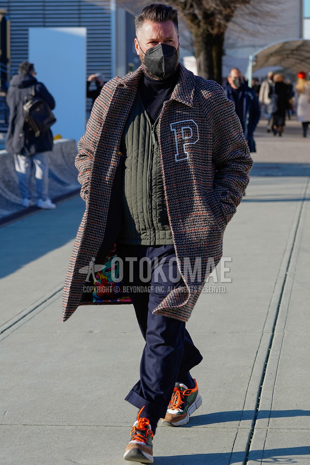 Men's spring winter outfit with brown check stenkarrer coat, olive green plain inner down, navy plain turtleneck knit, navy plain slacks, navy plain ankle pants, sneakers.