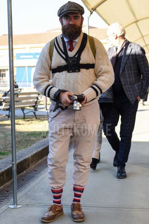 グレー無地のハンチングキャップ、チルデンの白無地のセーター、白無地のシャツ、グレー無地のスラックス、マルチカラーボーダーのソックス、ブラウン・ベージュウィングチップの革靴、ブラウン・ベージュブローグシューズの革靴、レッドネクタイのネクタイを合わせた春秋のメンズコーデ・着こなし。